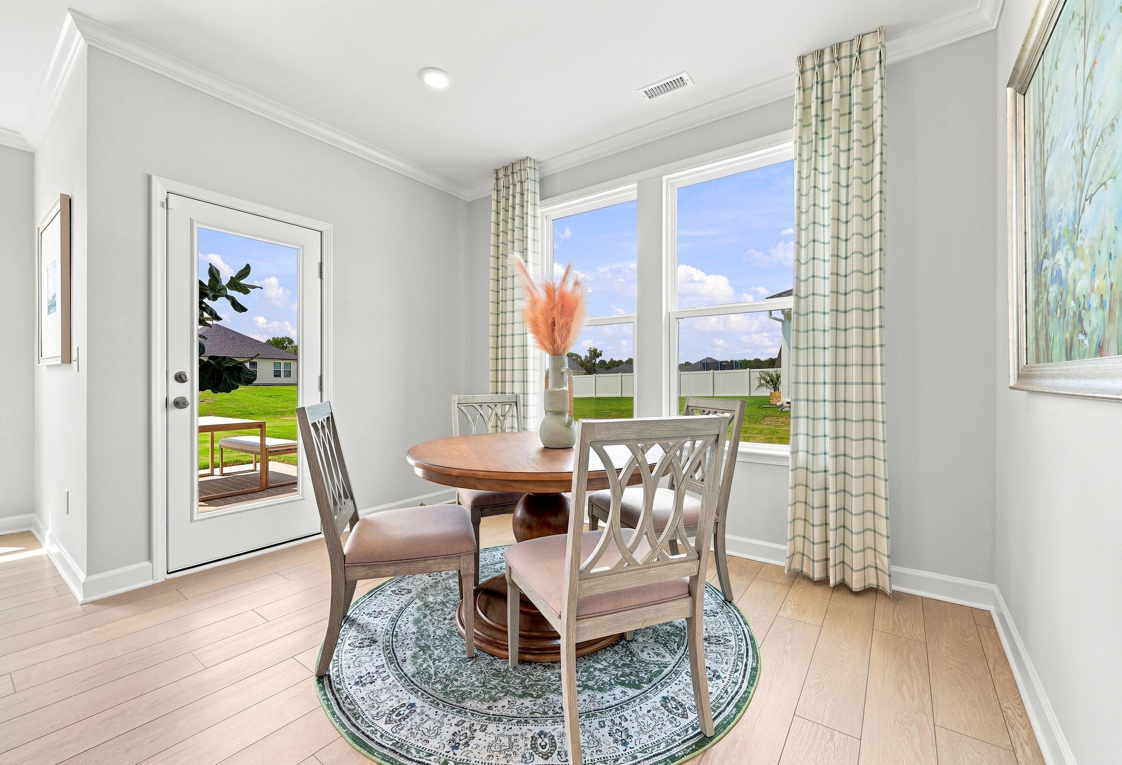 Bright breakfast nook in The Daphne C featuring a round dining table, patterned area rug, and access to the backyard.
