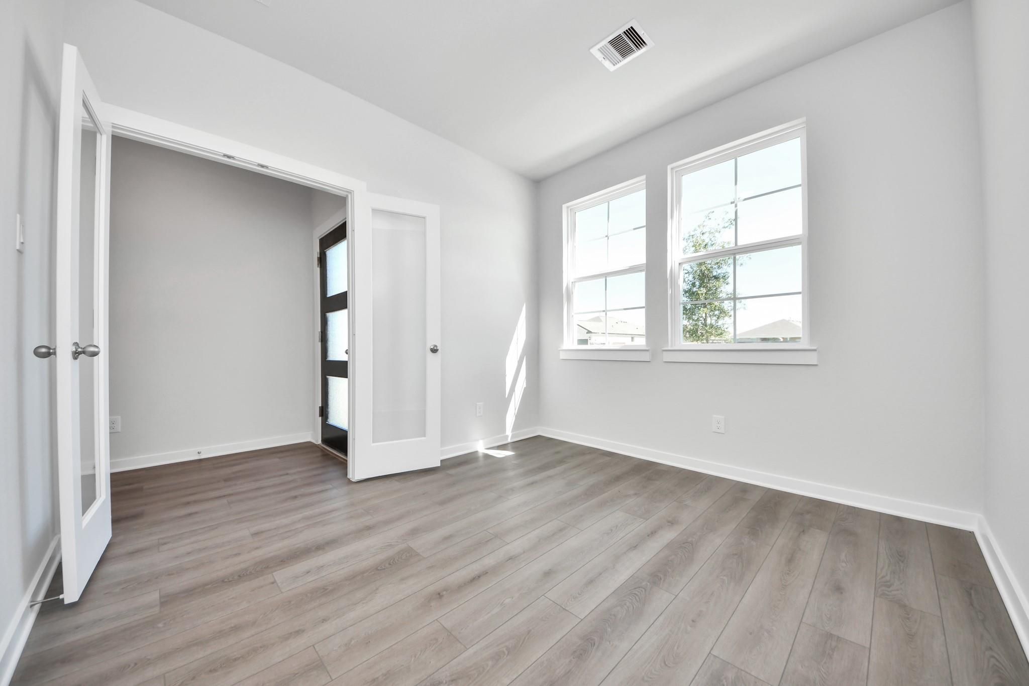 Bright home office or flex room with French doors and wood-look flooring in The Riviera A plan at Emberly, Beasley, Texas.