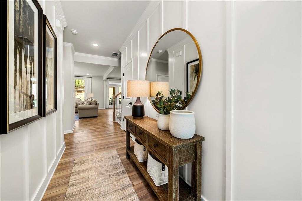 Elegant foyer with wooden console table, large gold mirror, framed art, and plants in 5-bedroom Davidson Homes The Hickory B, Riverwood, Dallas, Georgia
