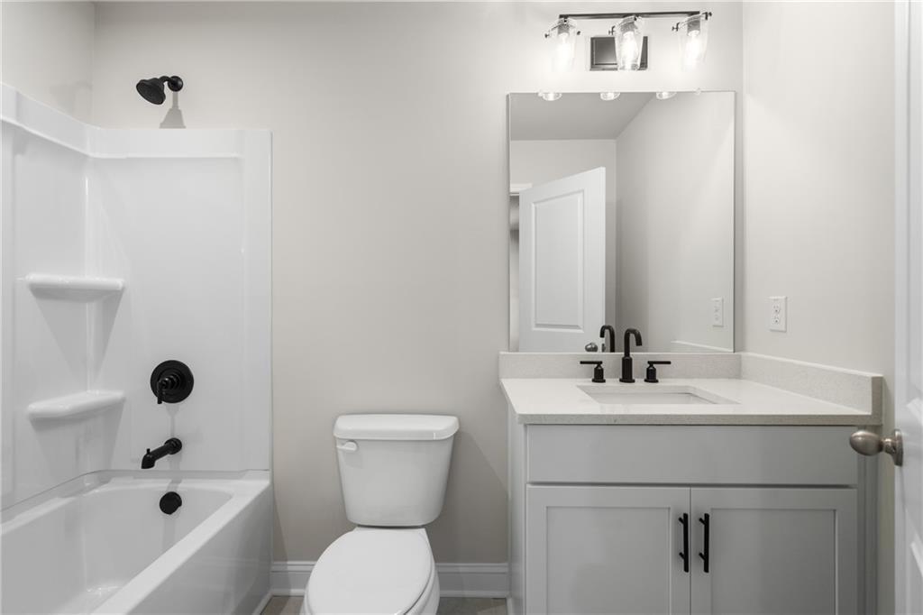 Modern bathroom with white tub-shower combo, quartz vanity, black fixtures in Davidson Homes The Hickory E, Buford, GA