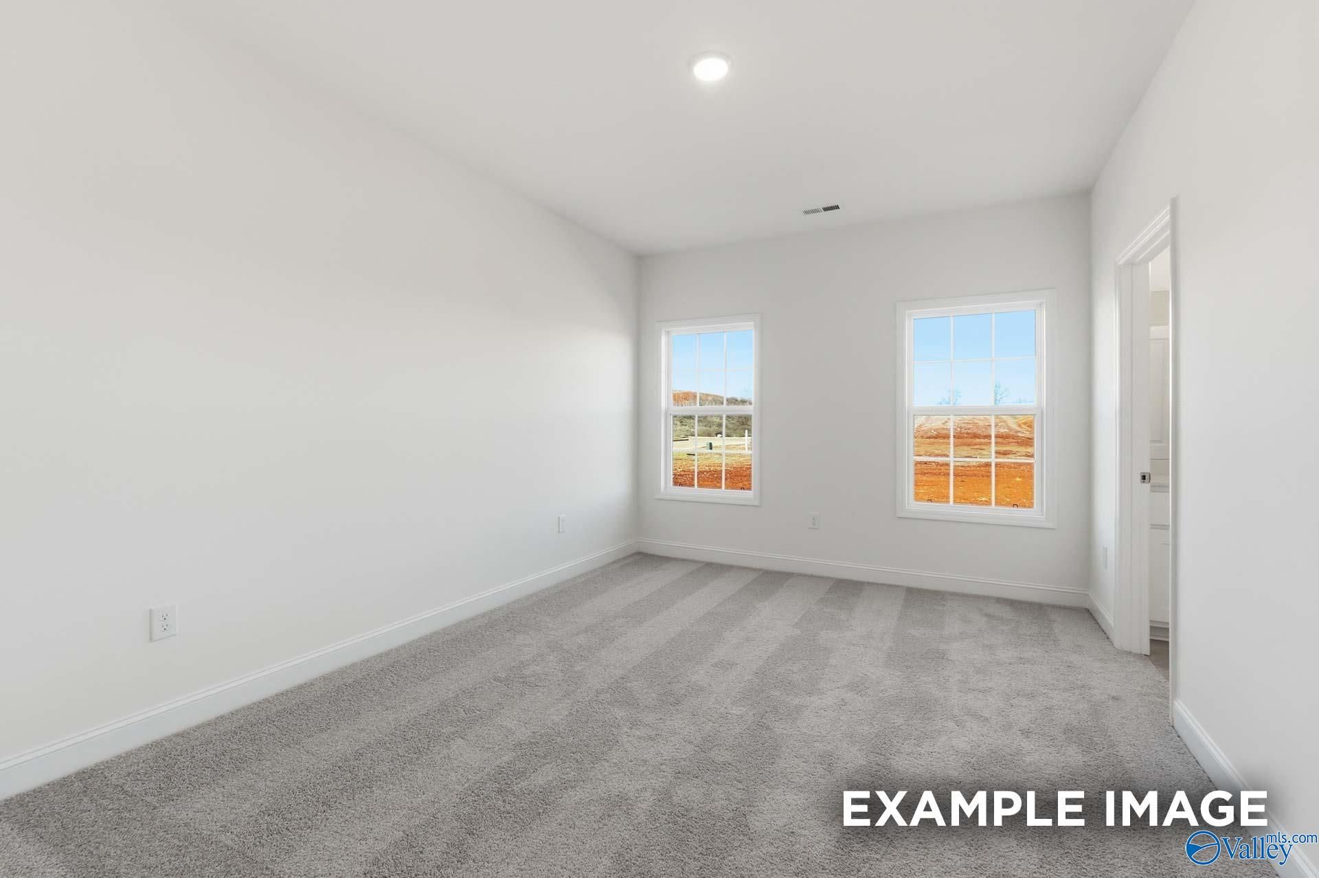 Bright bedroom with neutral carpet and large windows in The Valencia floor plan at Briercreek in Meridianville, Alabama.