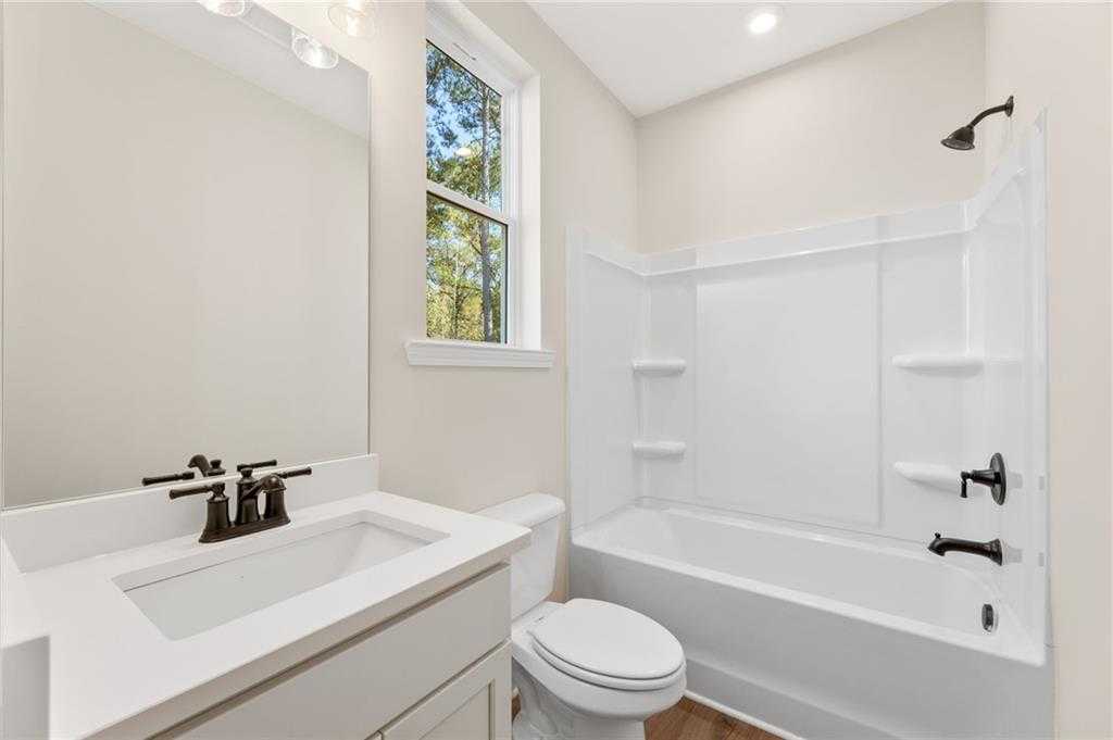Modern guest bathroom with white vanity, tub-shower combo, and tree-view window in 4-bedroom Davidson Homes The Daphne B, Loganville, GA