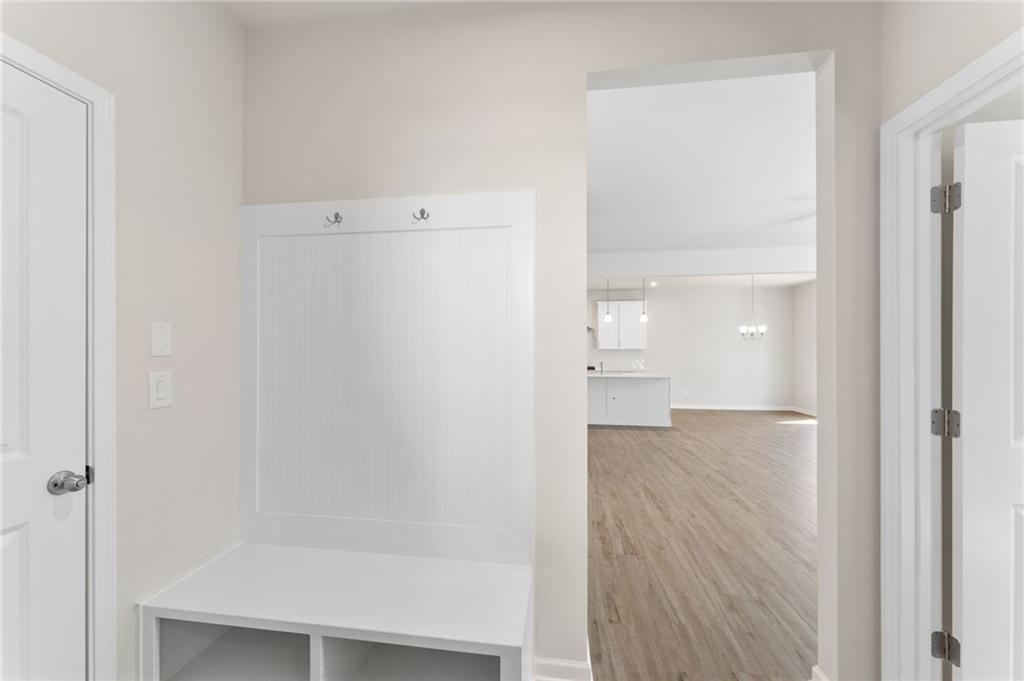 White mudroom with built-in bench, hooks, and storage opening to modern kitchen in Davidson Homes The Willow B, Riverwood, Dallas, GA