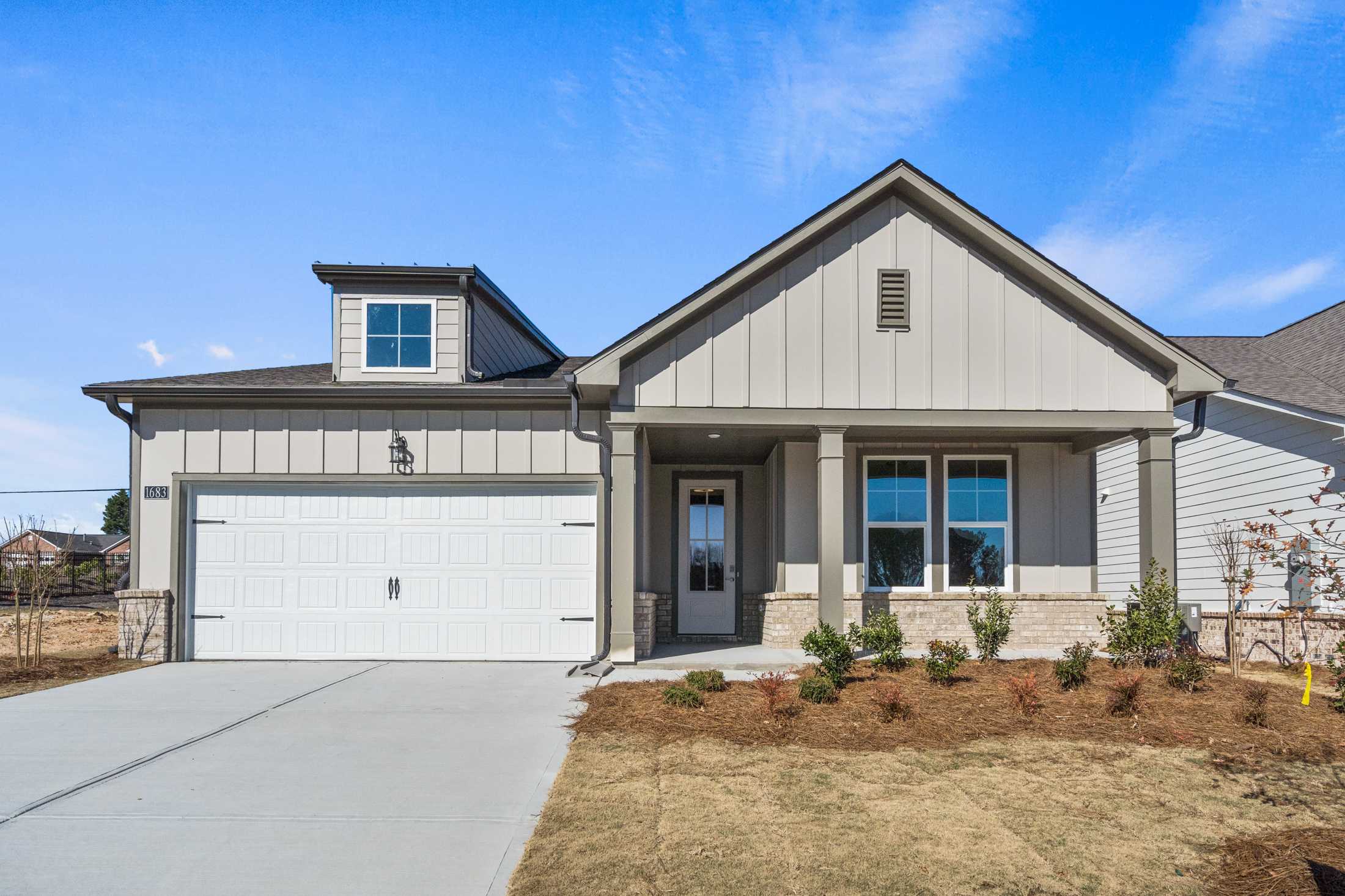 Modern gray siding exterior of The Dawson B single-story home with 2-car garage, covered porch, and dormer window in Loganville