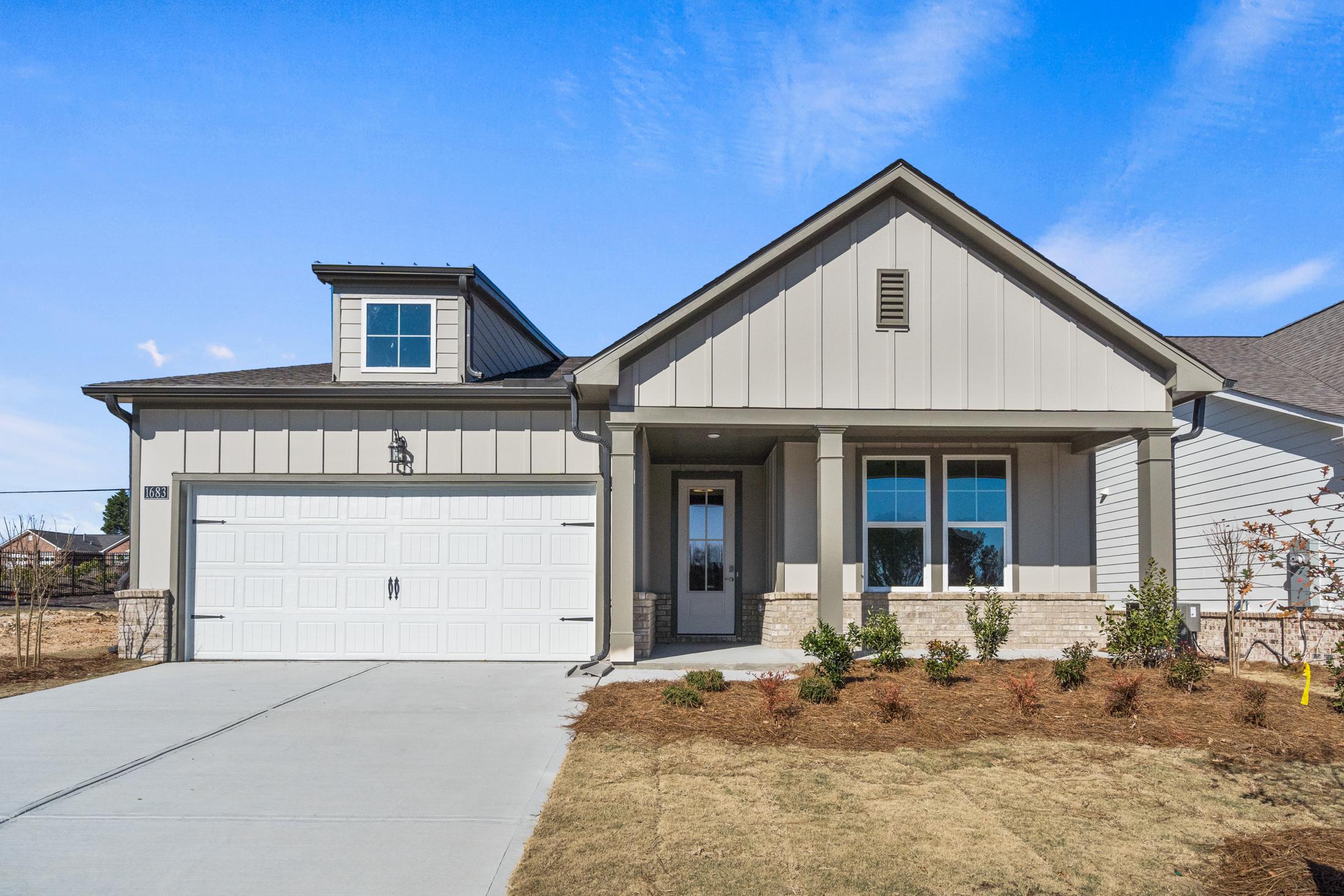 Modern gray siding exterior of The Dawson B single-story home with 2-car garage, covered porch, and dormer window in Loganville
