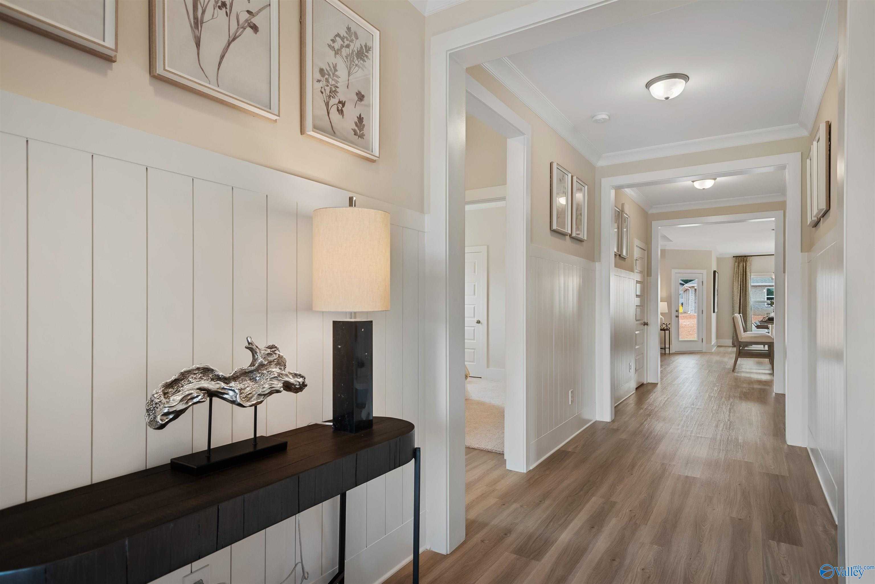 Elegant entry hallway with white shiplap walls, console table, lamp, and botanical art in Davidson Homes The Everett, New Market, Alabama