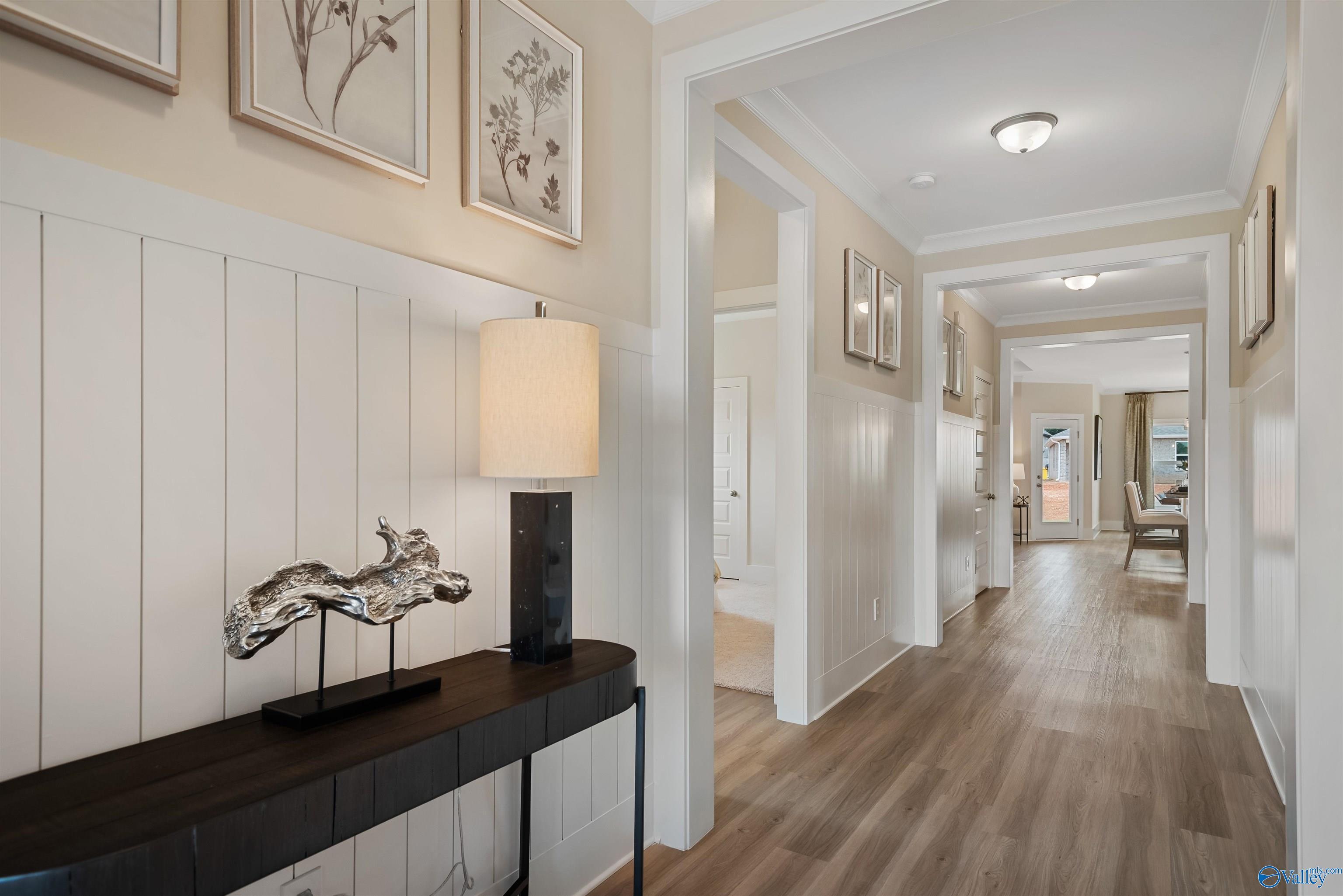 Elegant entry hallway with white shiplap walls, console table, lamp, and botanical art in Davidson Homes The Everett, New Market, Alabama