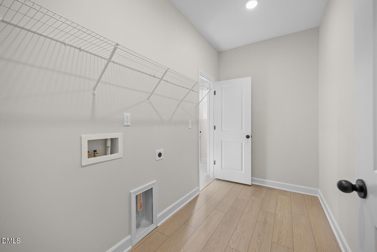 Spacious laundry room with wire shelving and wood-look flooring in Davidson Homes The Ashport M, Wendell Ridge, NC