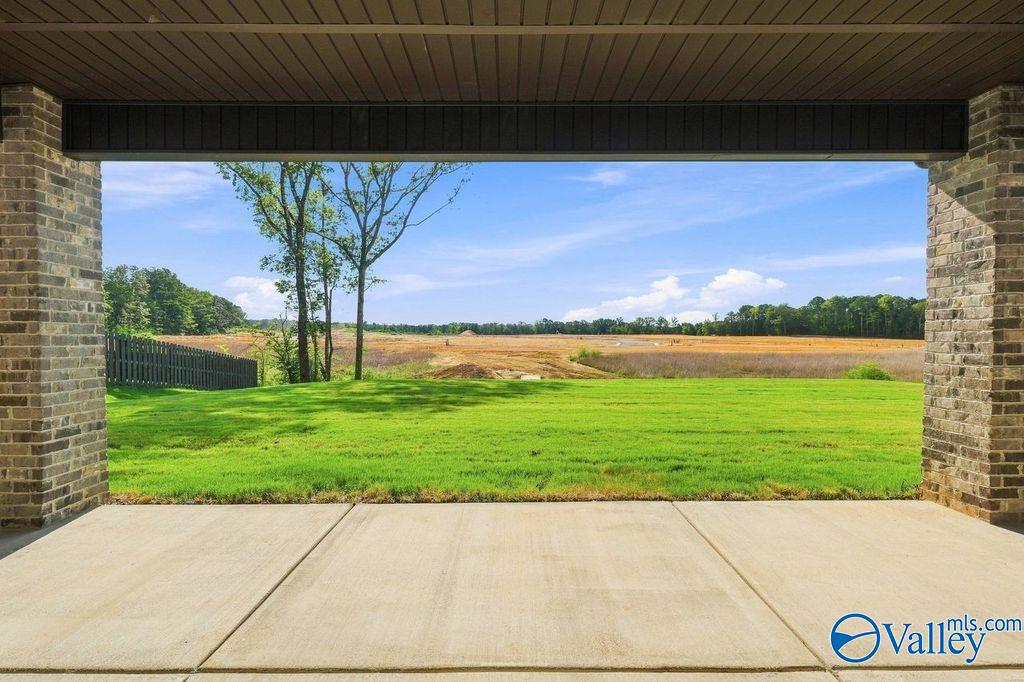 Covered brick patio overlooking a spacious backyard and scenic landscape at The Rockford home in Cain Park, Hartselle, AL.
