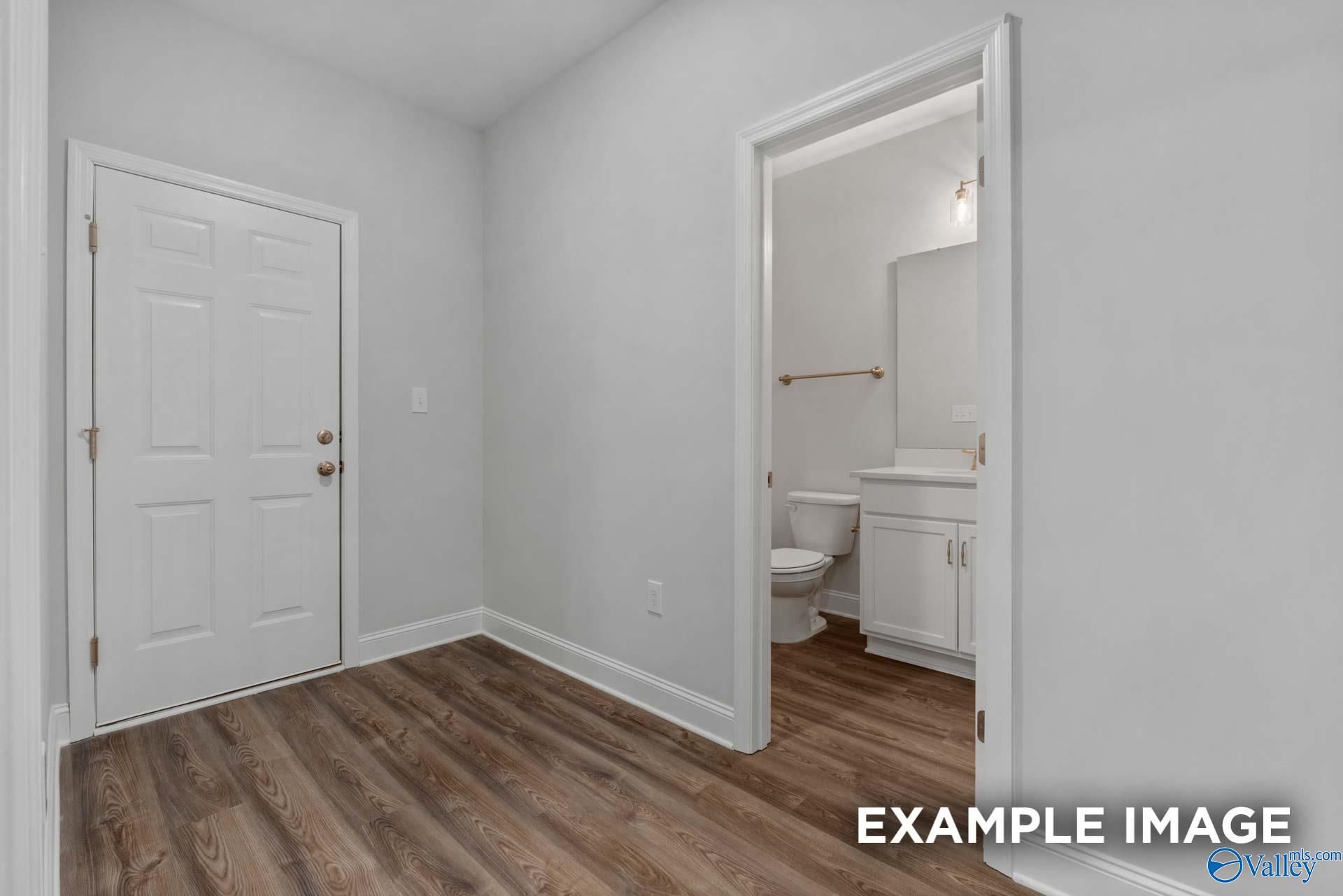 Bright guest bathroom featuring white vanity, toilet, brass accents, and wood-look flooring in The Shelby C, Arab, Alabama