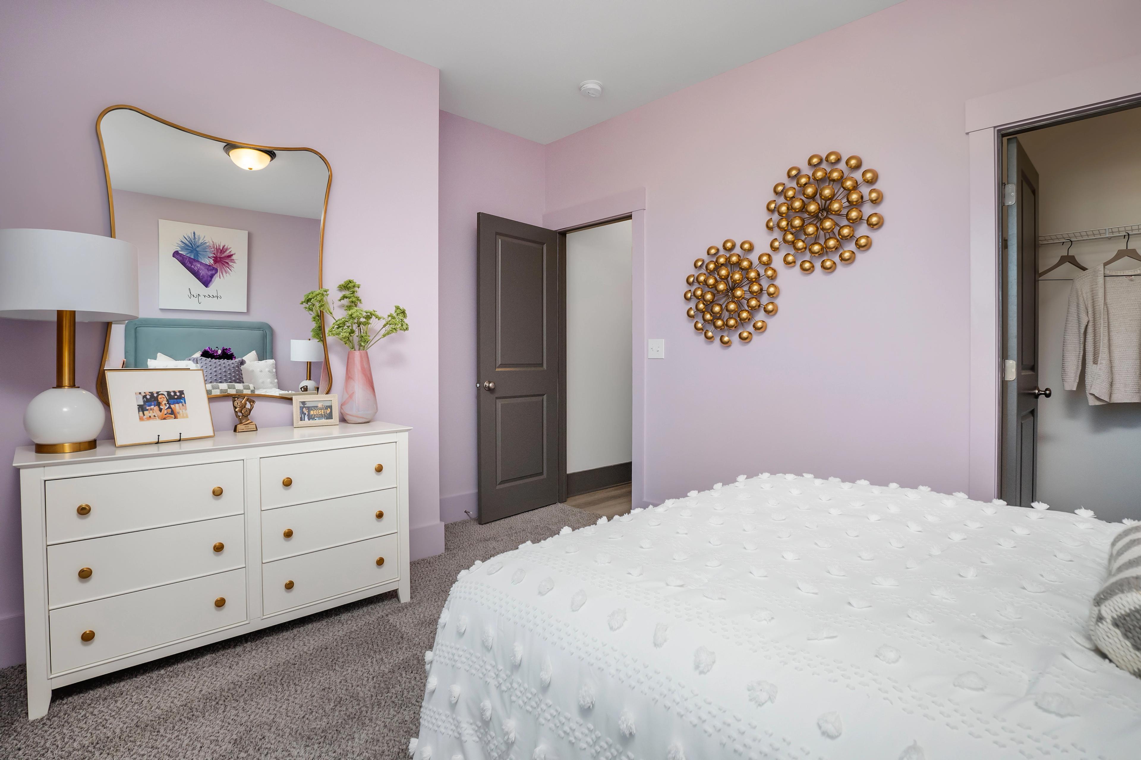 Lavender bedroom interior at Barnett's Crossing in Madison AL with white tufted bed, gold accents, and vanity