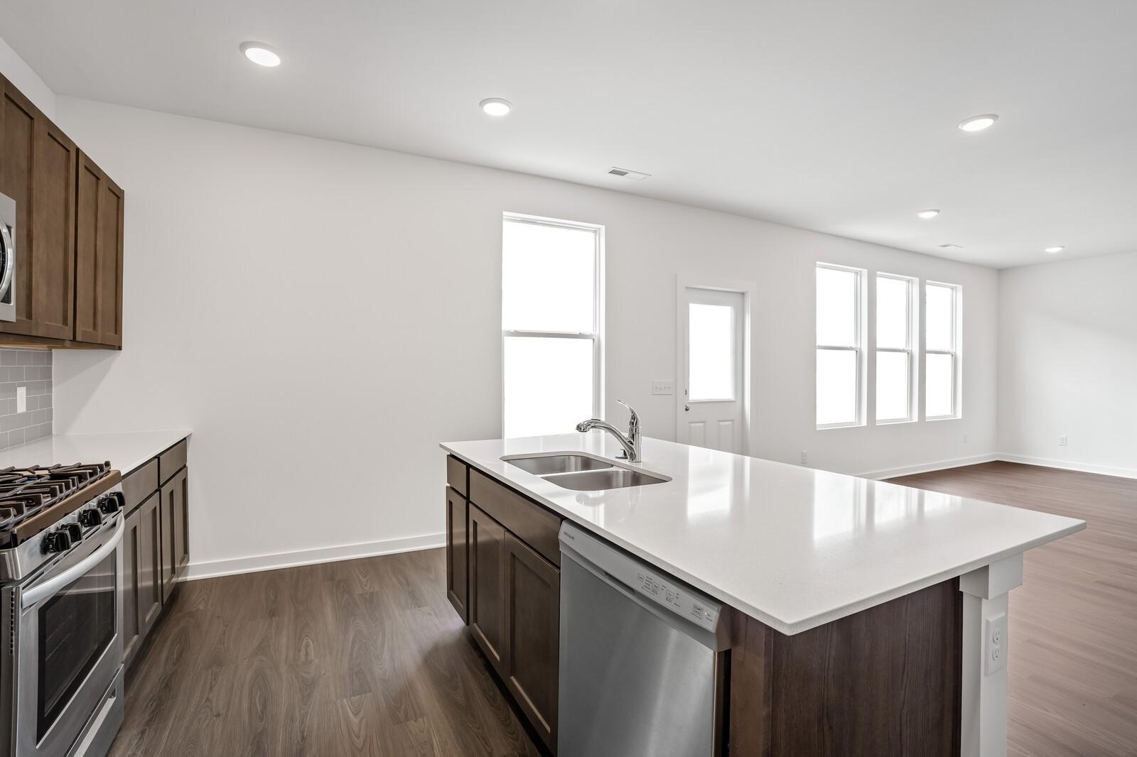 Modern kitchen featuring white quartz island, stainless steel appliances, and hardwood floors in Davidson Homes The Logan C, White House, TN