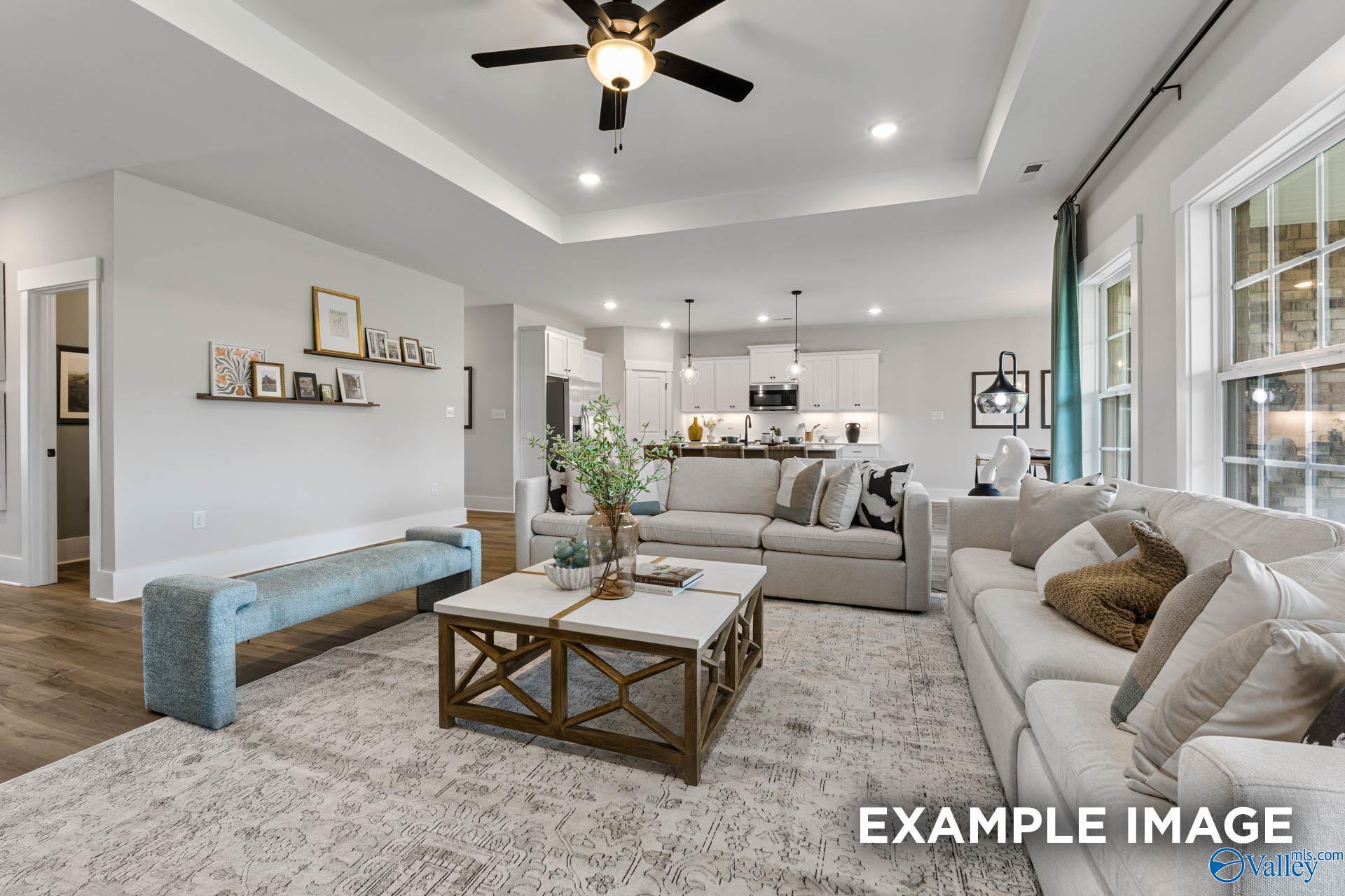 Open-concept living room with tray ceiling and modern kitchen in The Rockford floor plan by Davidson Homes in Hartselle.