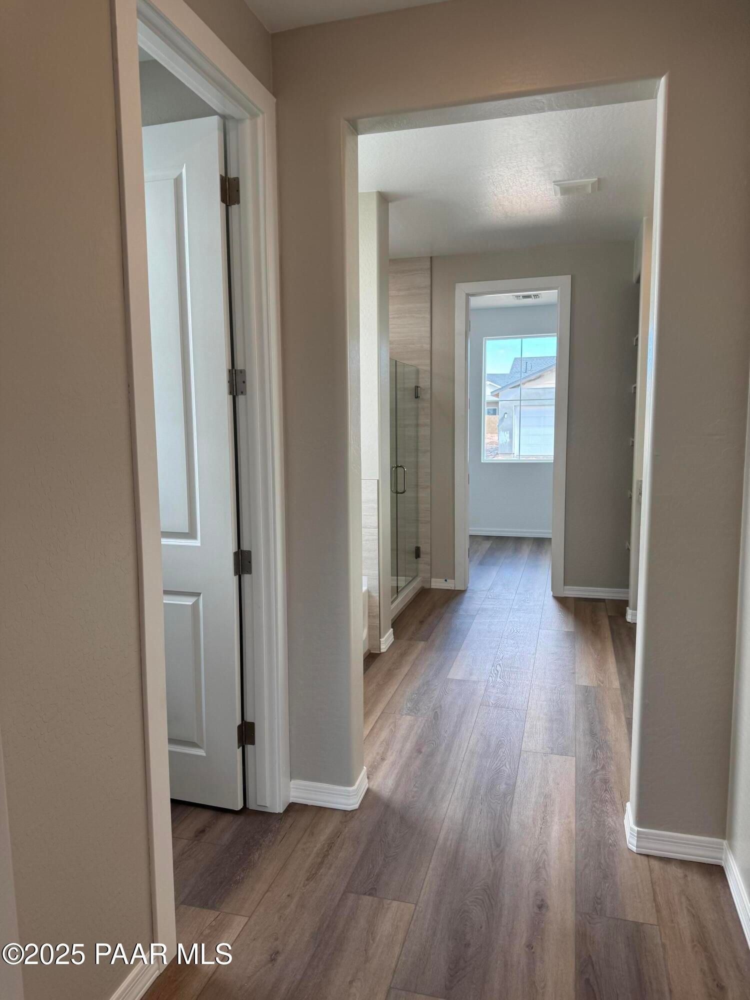 Elegant hallway with luxury vinyl plank flooring and glass shower enclosure in Davidson Homes The Monarch A, Prescott Arizona