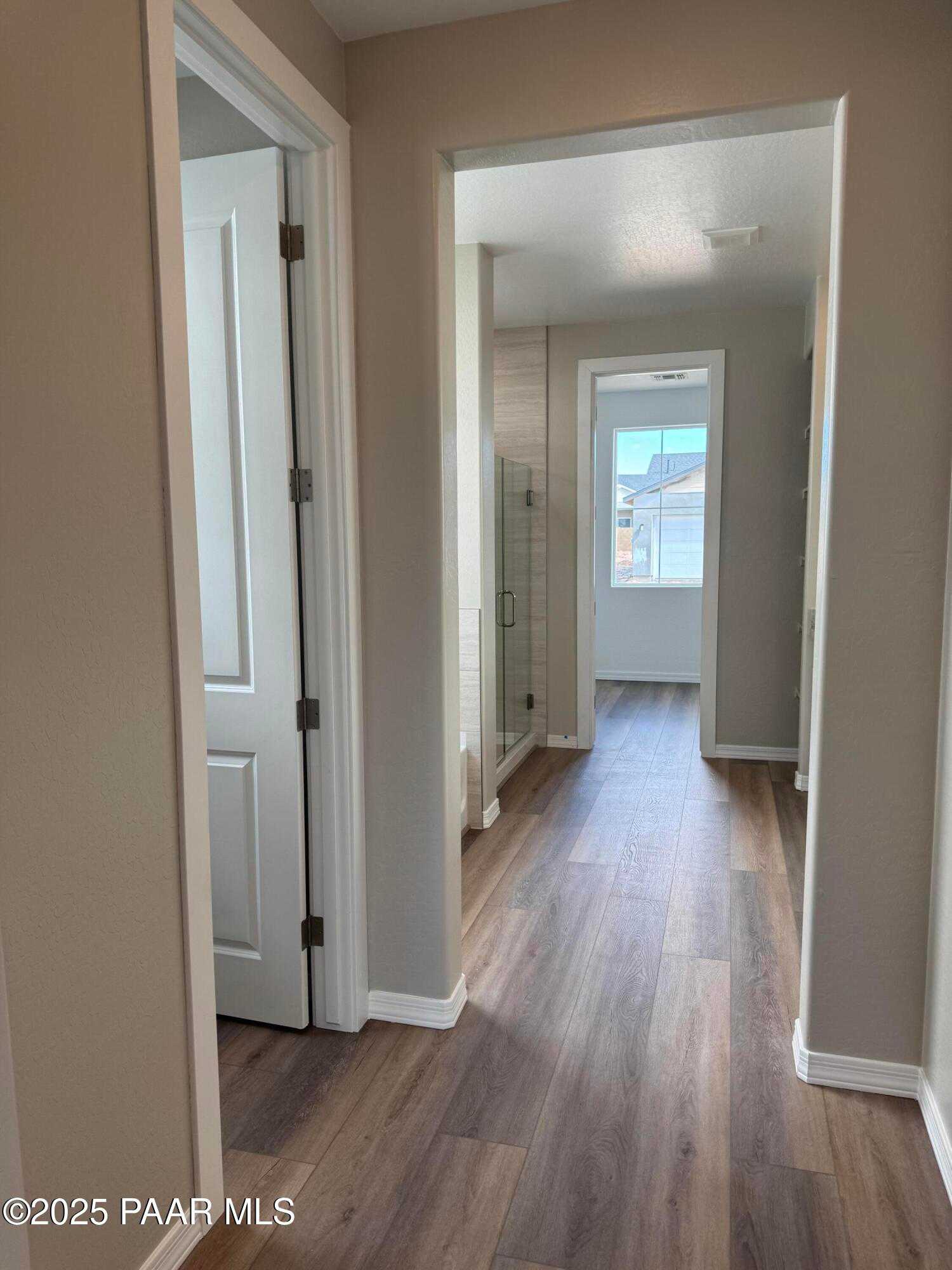 Elegant hallway with luxury vinyl plank flooring and glass shower enclosure in Davidson Homes The Monarch A, Prescott Arizona