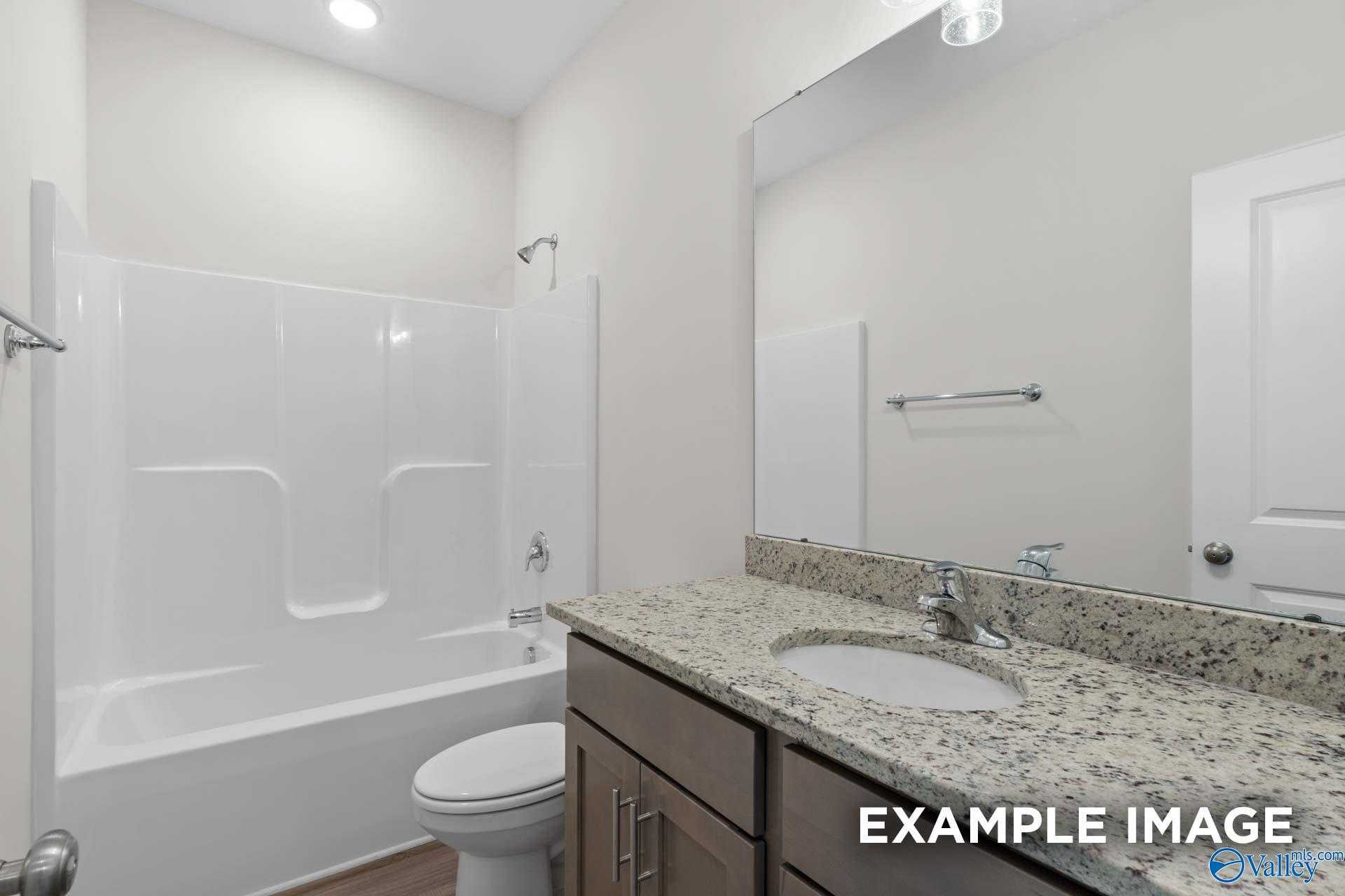 Modern bathroom with granite vanity, soaking tub, tiled shower, and large mirror in Davidson Homes The Daphne D, Arab, Alabama