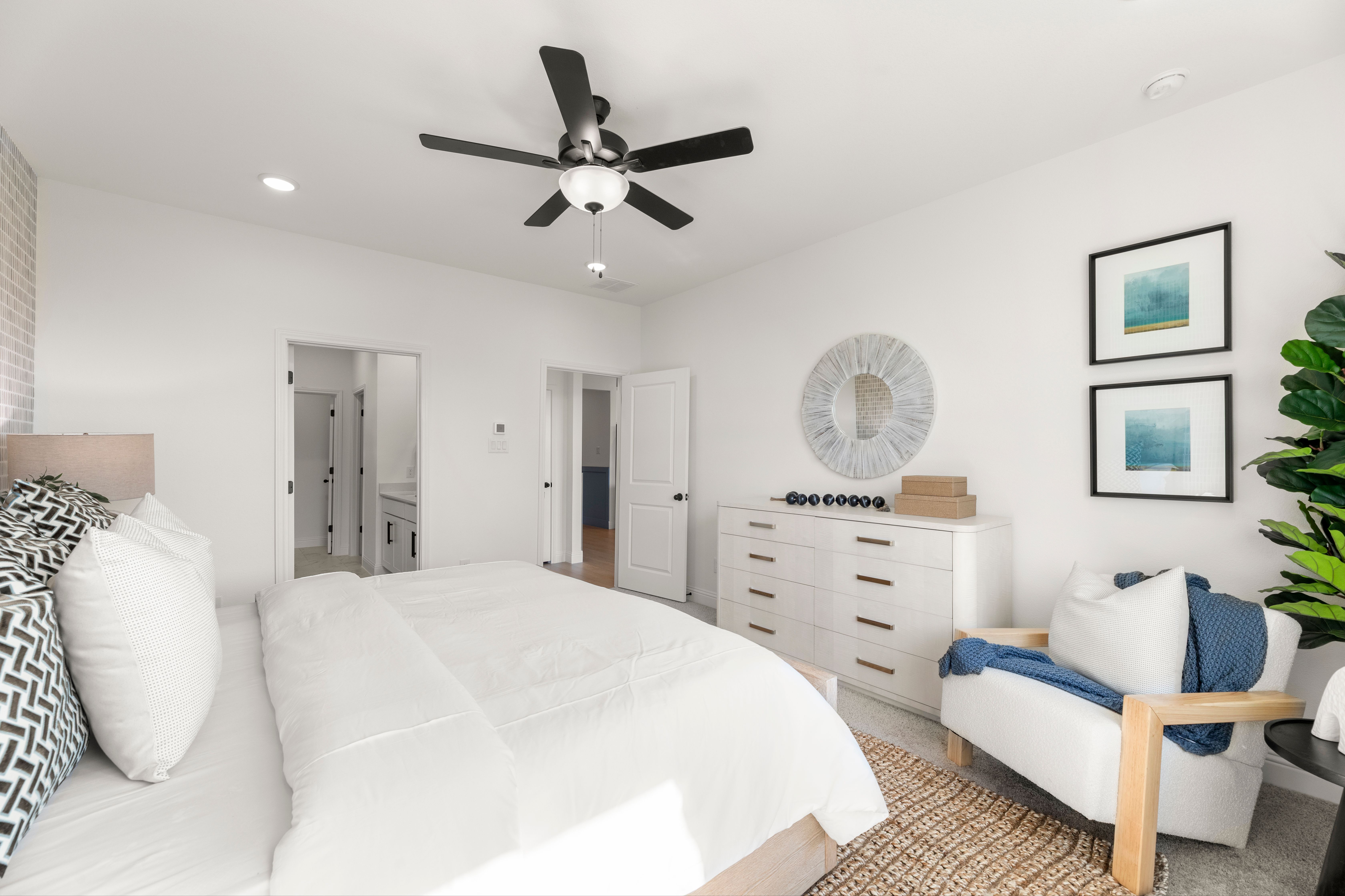 Spacious master bedroom in The Laurel I featuring king bed, ceiling fan, modern dresser, armchair, and en-suite bath door