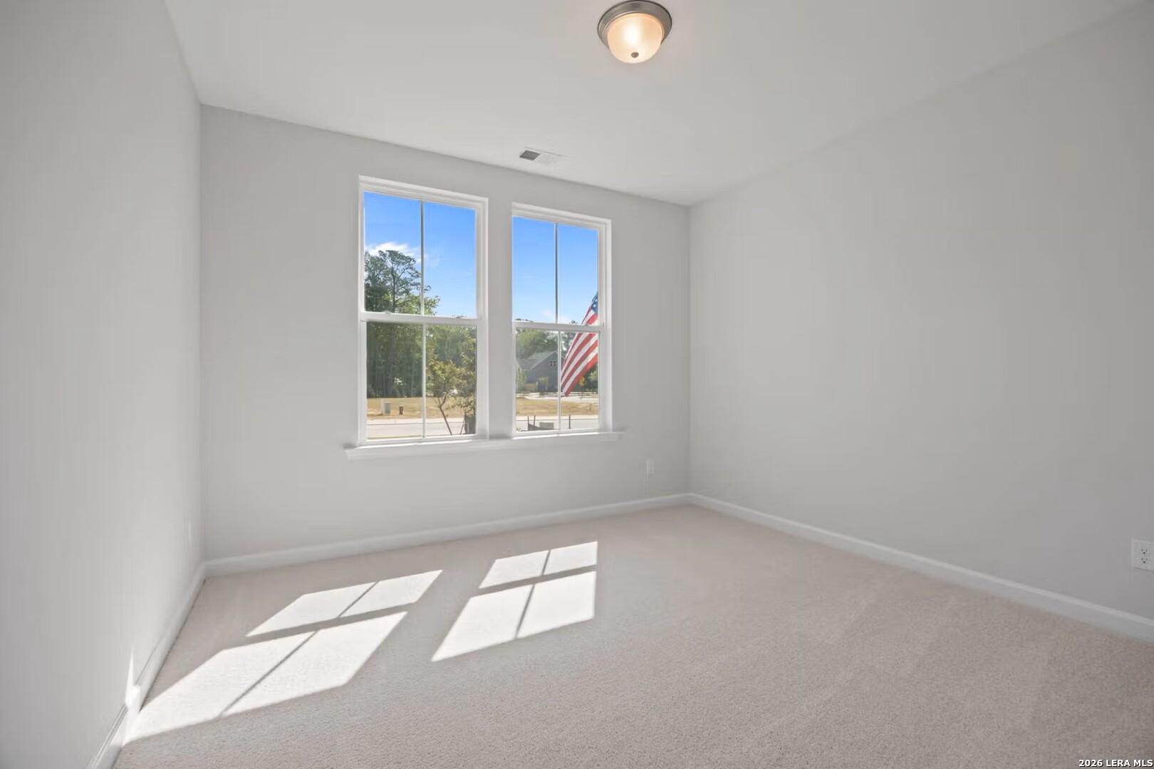 Bright, carpeted bedroom with large windows in The Ashport F floor plan at Morgan Meadows, San Antonio, Texas.