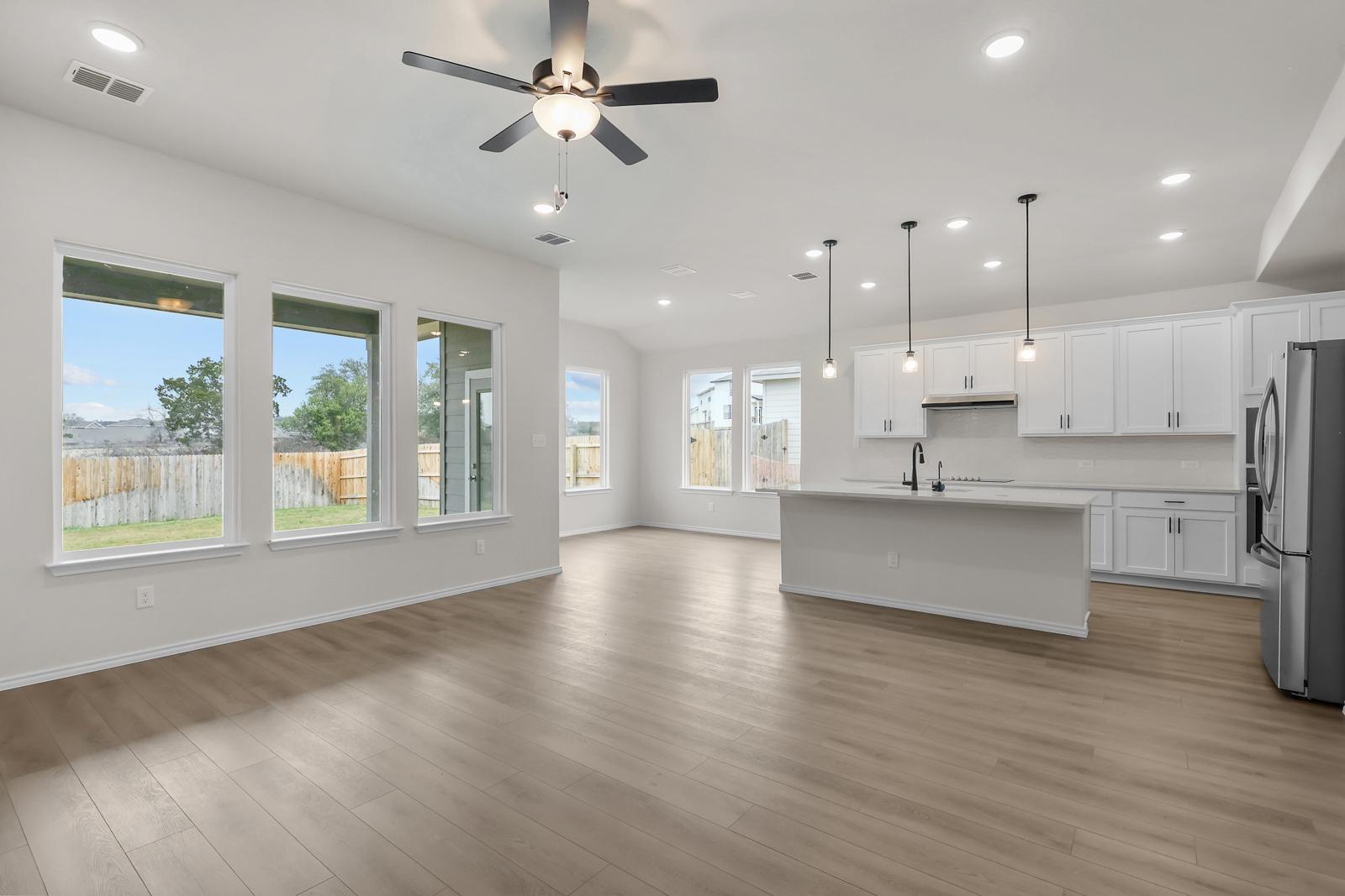 Open-concept kitchen and living area in The Sequoia C with modern white cabinetry, large island, and natural lighting.