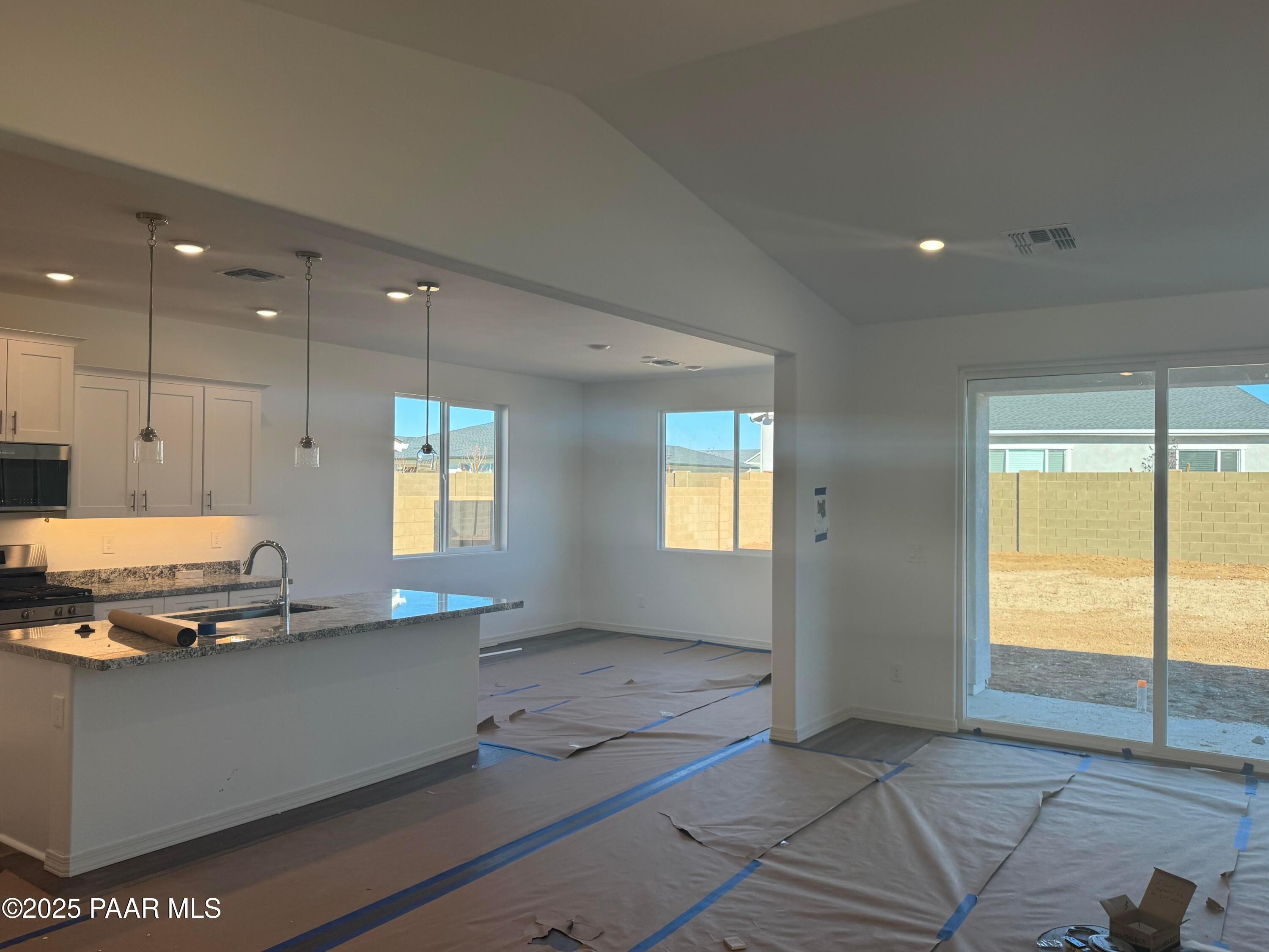 Open-concept kitchen with granite island, white cabinets, stainless appliances, and desert-view sliding doors in Davidson Homes Summit A, Prescott AZ