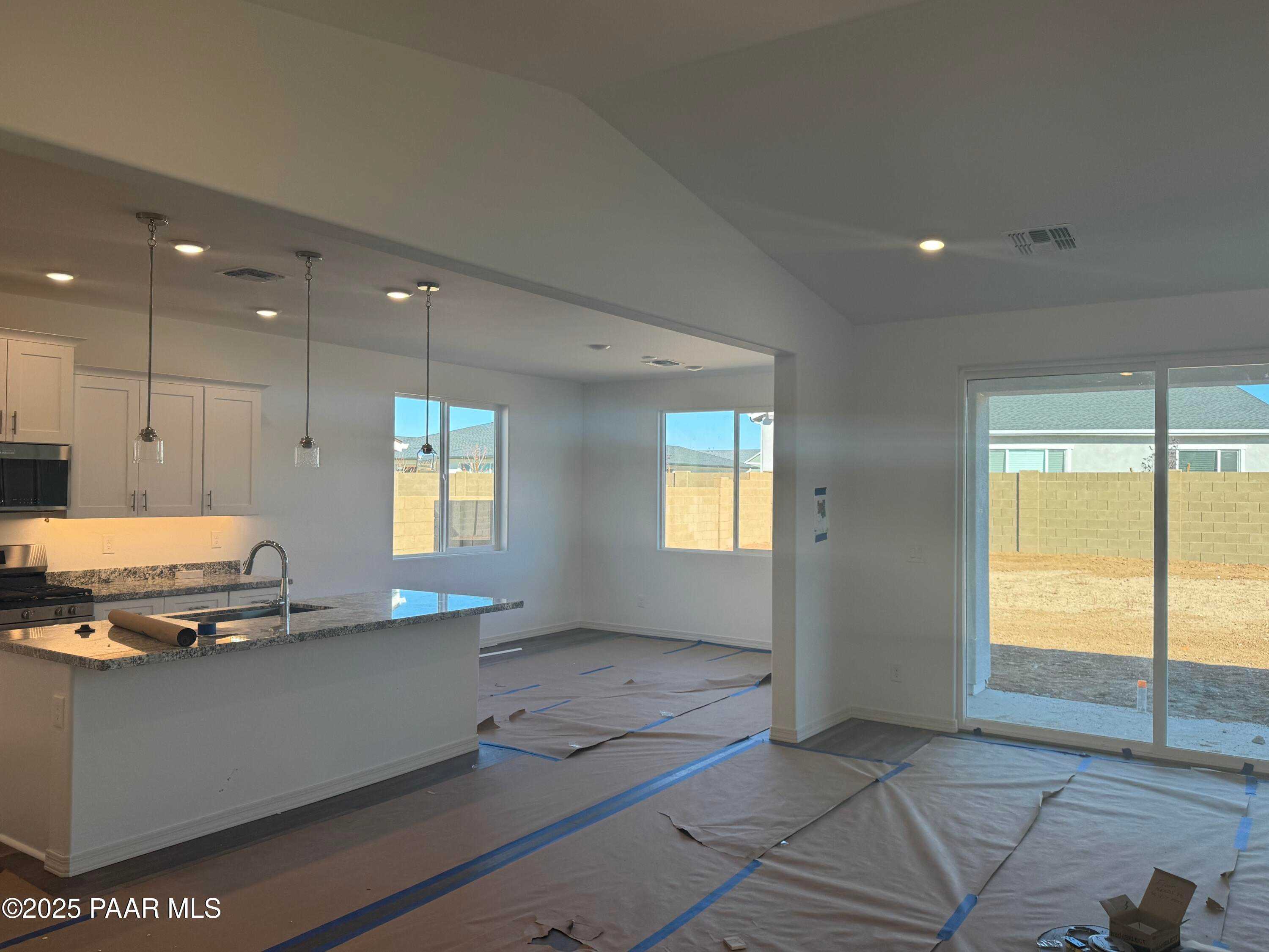 Open-concept kitchen with granite island, white cabinets, stainless appliances, and desert-view sliding doors in Davidson Homes Summit A, Prescott AZ