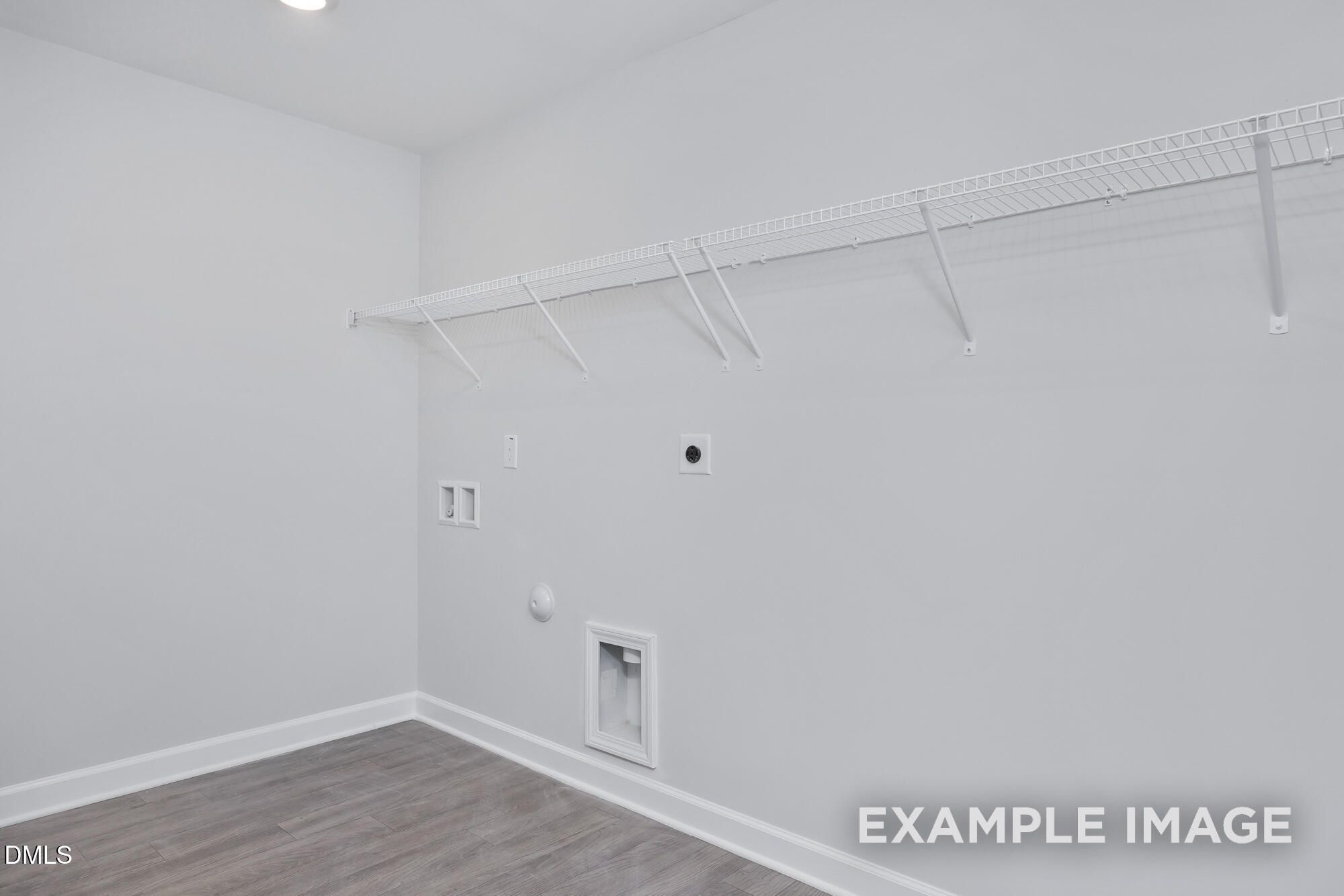 Spacious laundry room with wire shelving, utility hookups, and hardwood floors in Hickory II B home, Lillington, NC