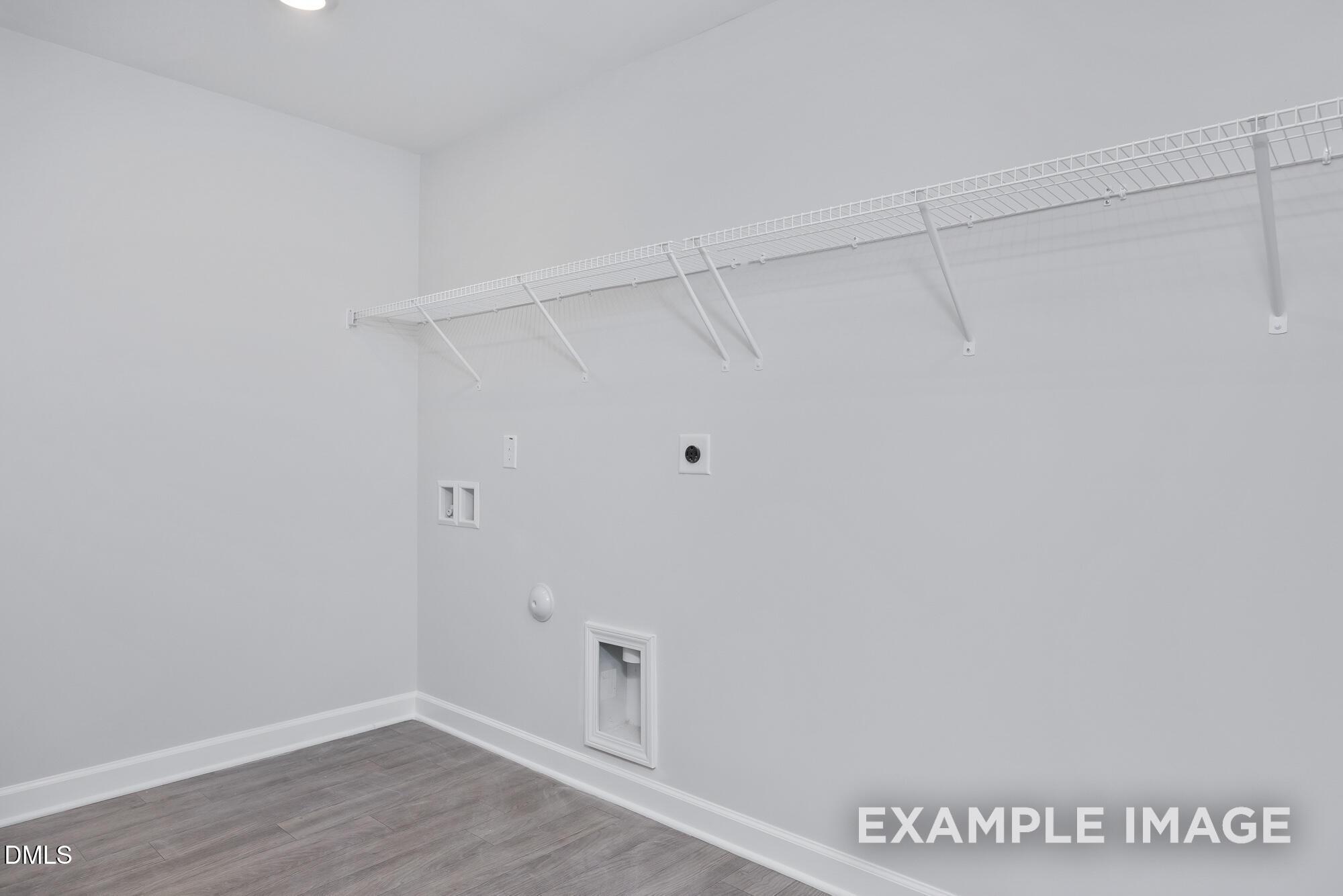 Spacious laundry room with wire shelving, utility hookups, and hardwood floors in Hickory II B home, Lillington, NC