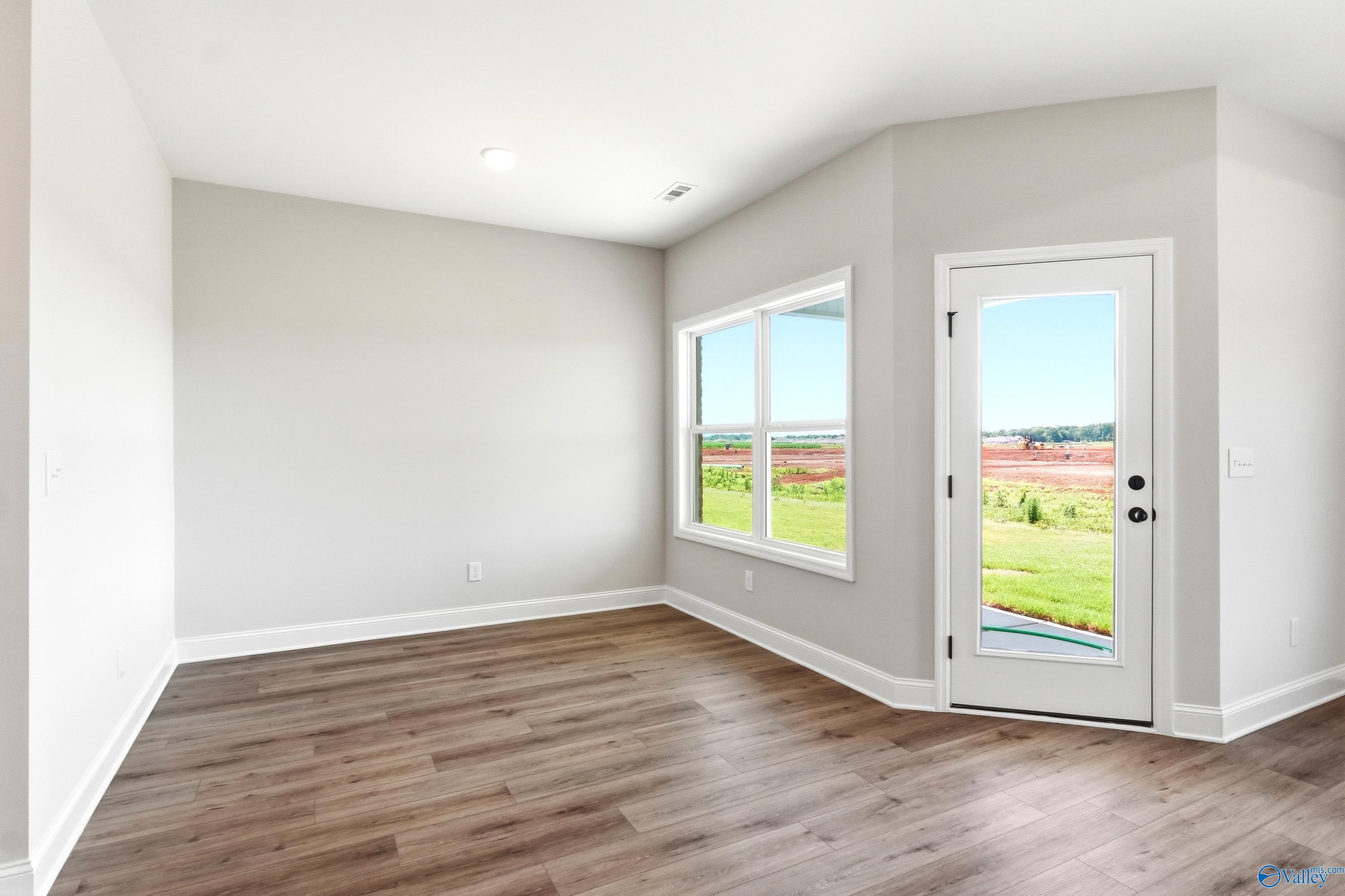 Bright living area with wood-look flooring and backyard access in The Daphne floor plan at Clearview, Hazel Green, Alabama.