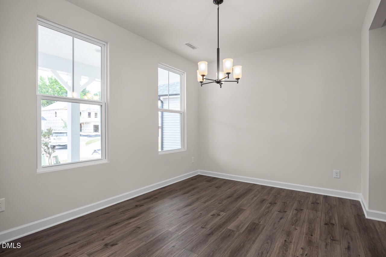 Bright dining room with modern chandelier and wood-look flooring in The Willow B plan at Woodland Crossing, Zebulon, NC.