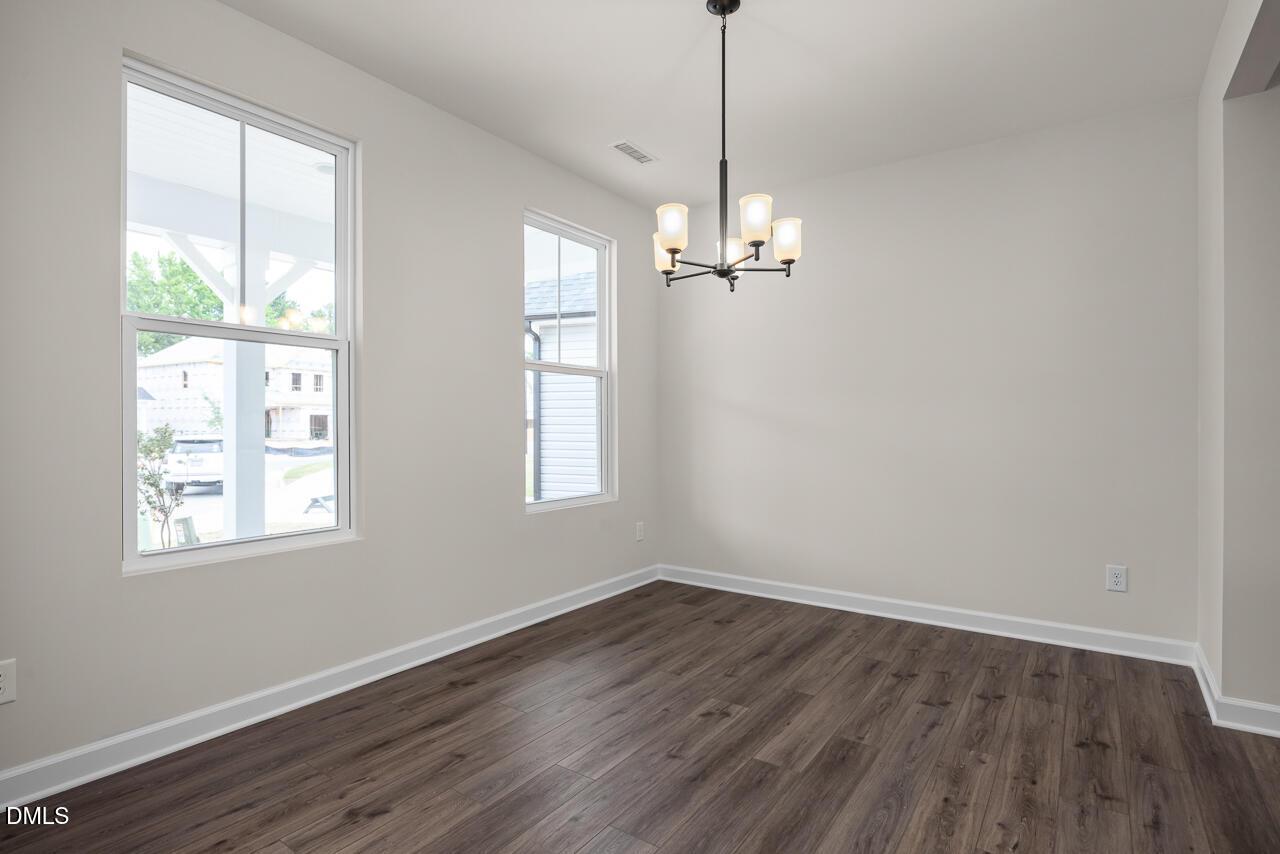 Bright dining room with modern chandelier and wood-look flooring in The Willow B plan at Woodland Crossing, Zebulon, NC.