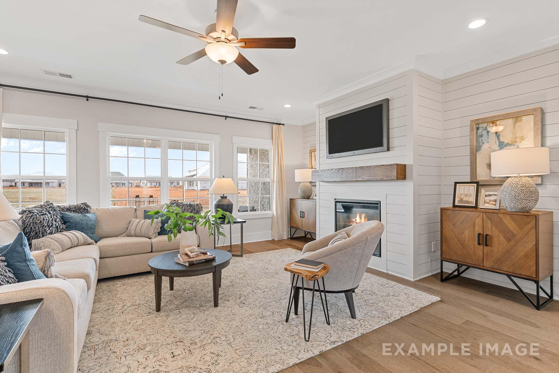 Cozy living room in The Rockford home by Davidson Homes featuring beige sectional sofa, shiplap walls, gas fireplace, and large windows in Meridianville AL
