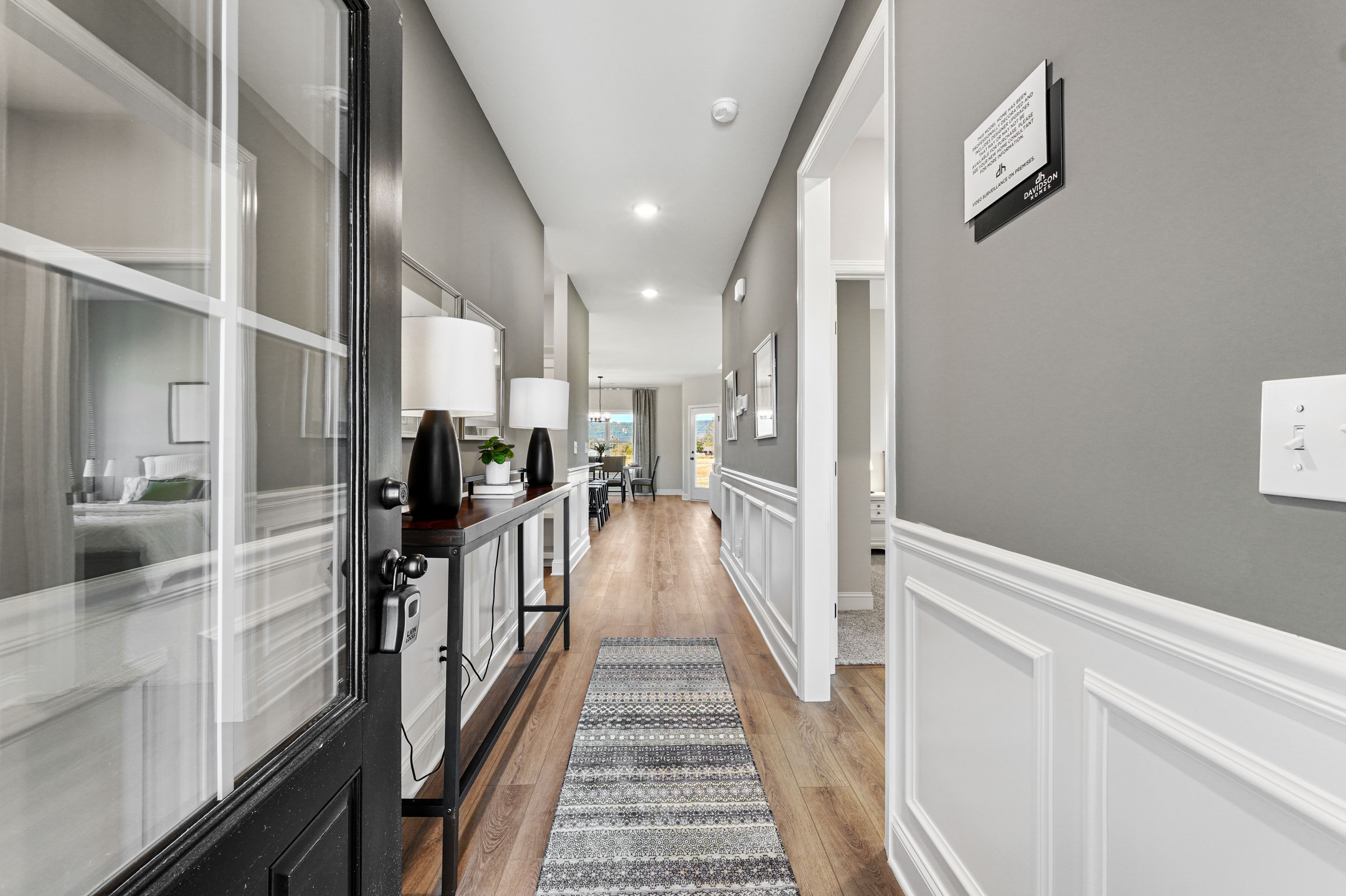Spacious modern hallway at Ramsay Cove in Owens Cross Roads AL with hardwood floors, gray walls, runner rug, and console table