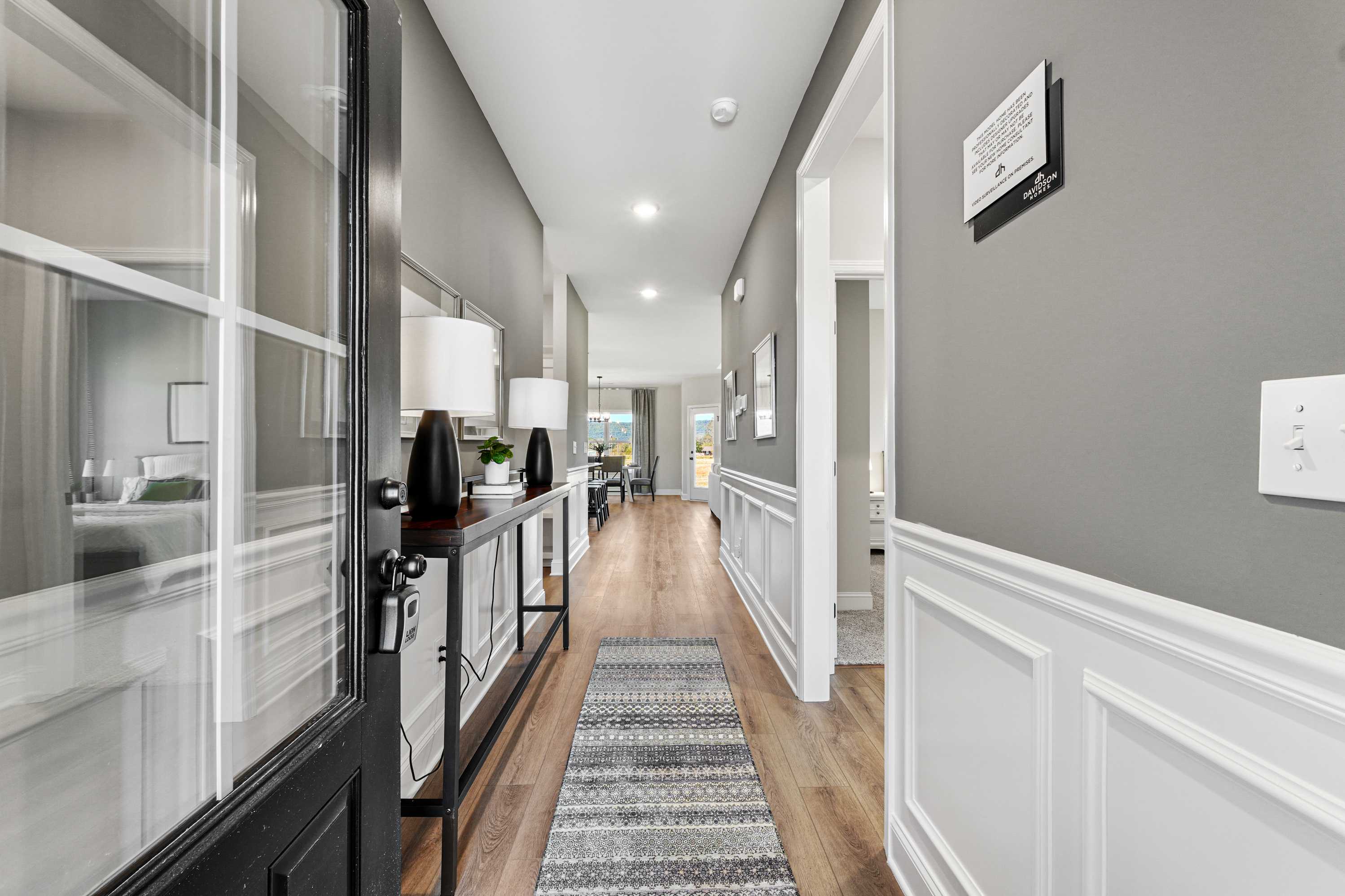 Spacious modern hallway at Ramsay Cove in Owens Cross Roads AL with hardwood floors, gray walls, runner rug, and console table