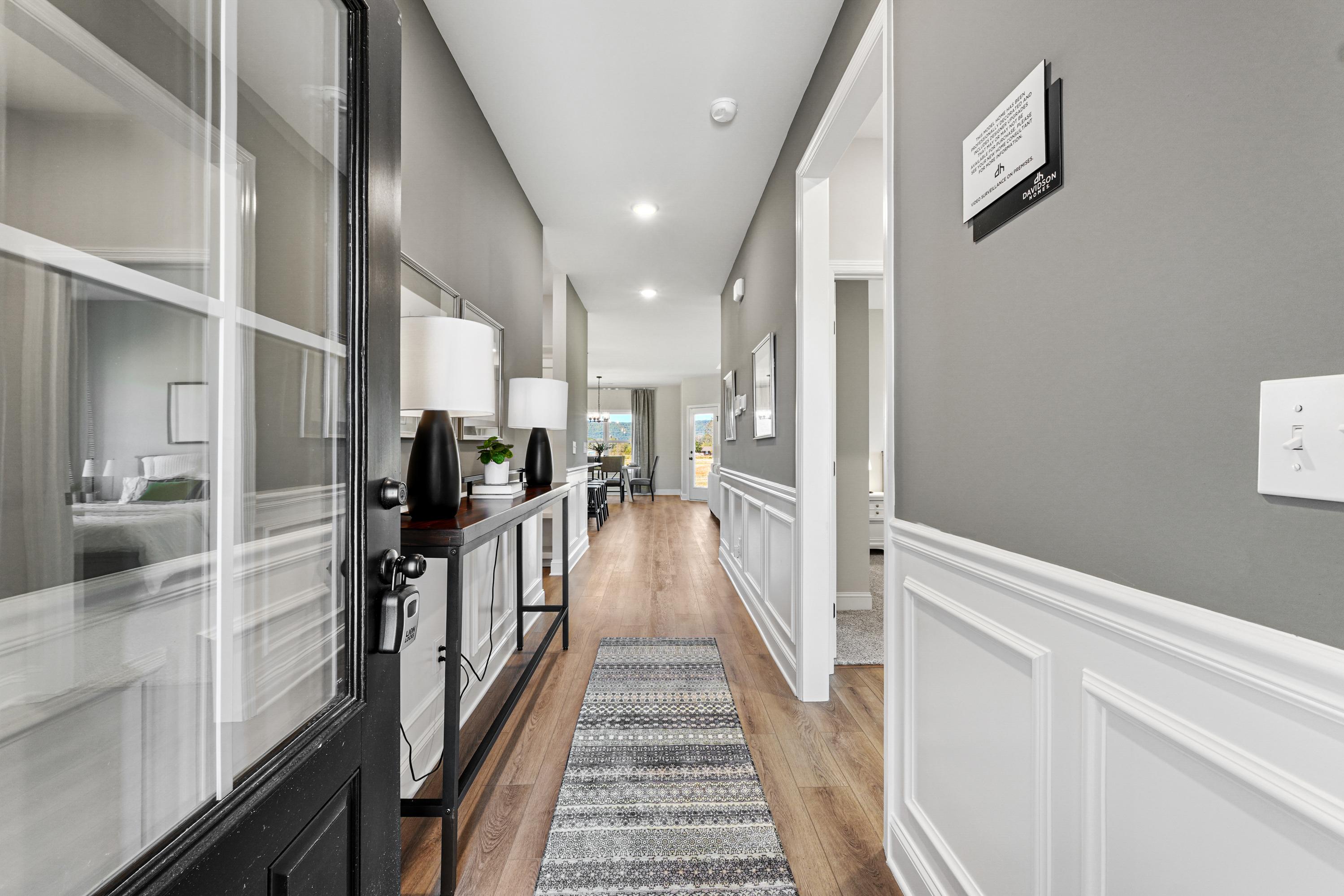 Spacious modern hallway at Ramsay Cove in Owens Cross Roads AL with hardwood floors, gray walls, runner rug, and console table