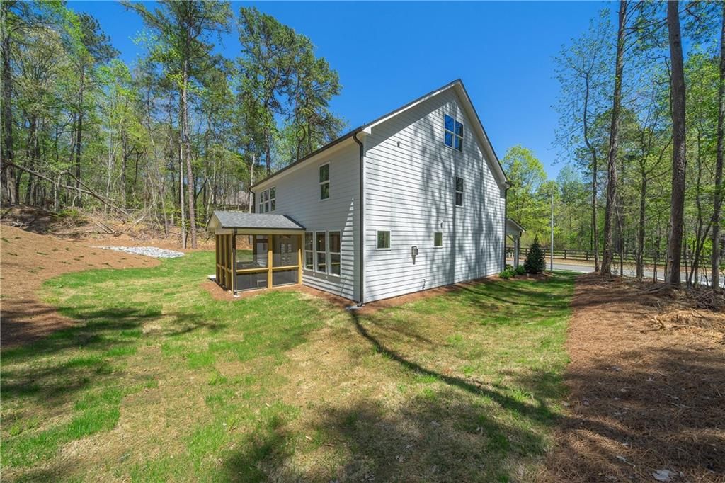 Two-story white home with screened porch and gabled roof amid pines in Riverwood, Dallas, Georgia - Davidson Homes Willow B