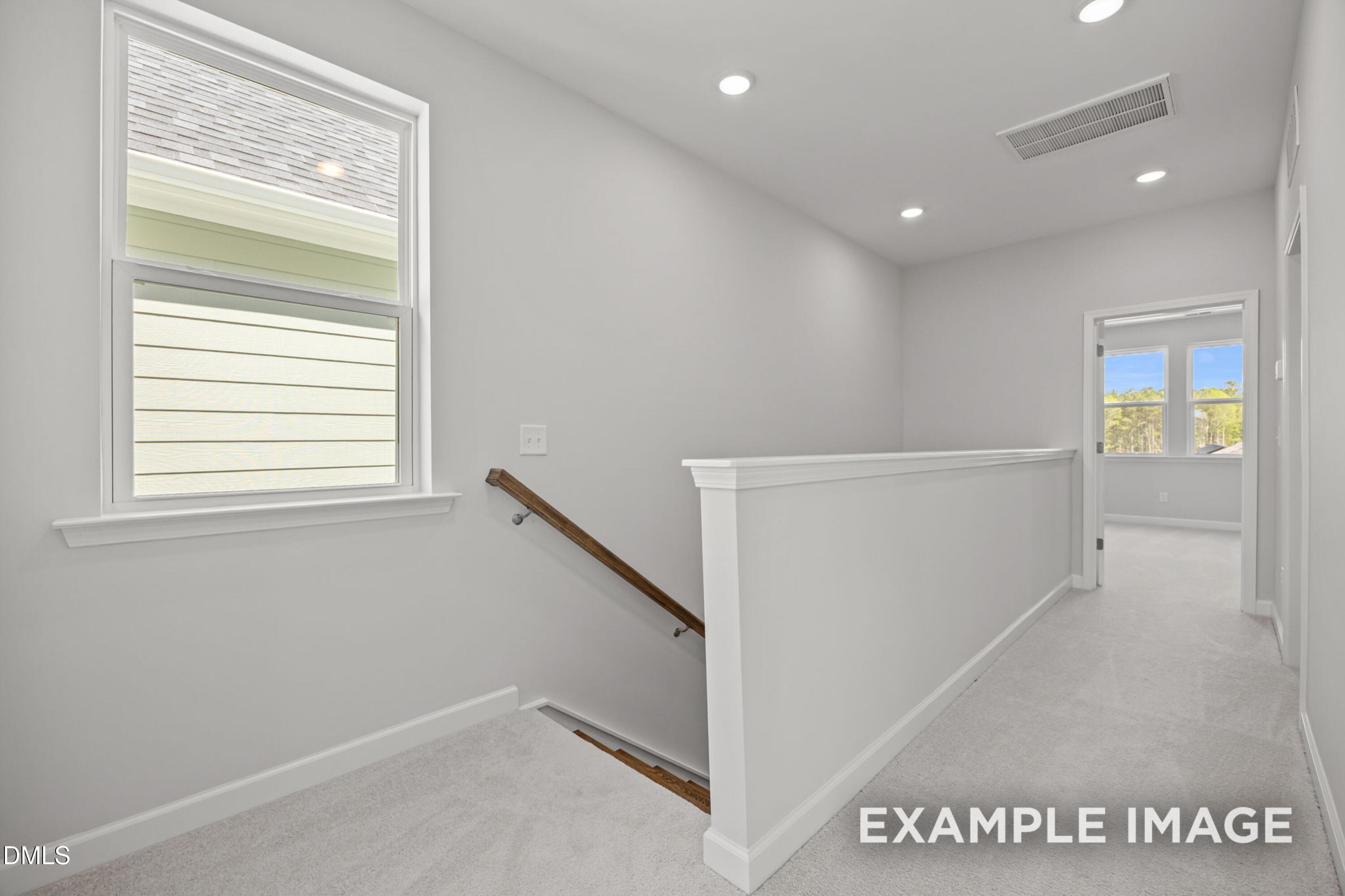 Bright upstairs landing with carpet and staircase in The Alexander B floor plan at Forestville Yard in Knightdale, NC.