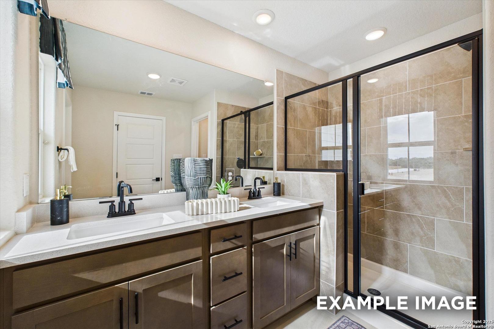 Modern master bathroom featuring double vanity, frameless glass shower, and neutral tile in Davidson Homes The Florence C, San Antonio