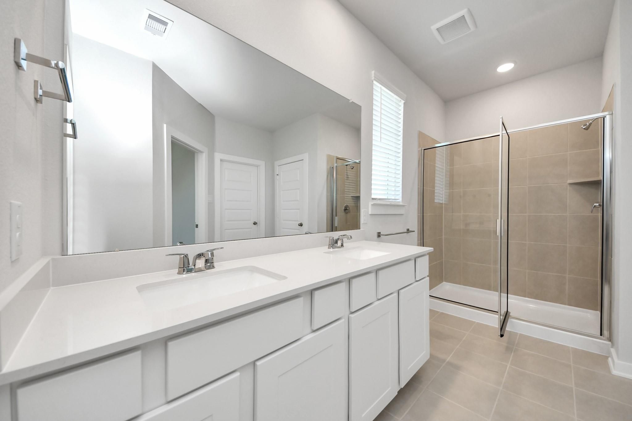 Modern bathroom with double vanity and walk-in shower in Davidson Homes The Costa A plan at Emberly, Beasley, Texas