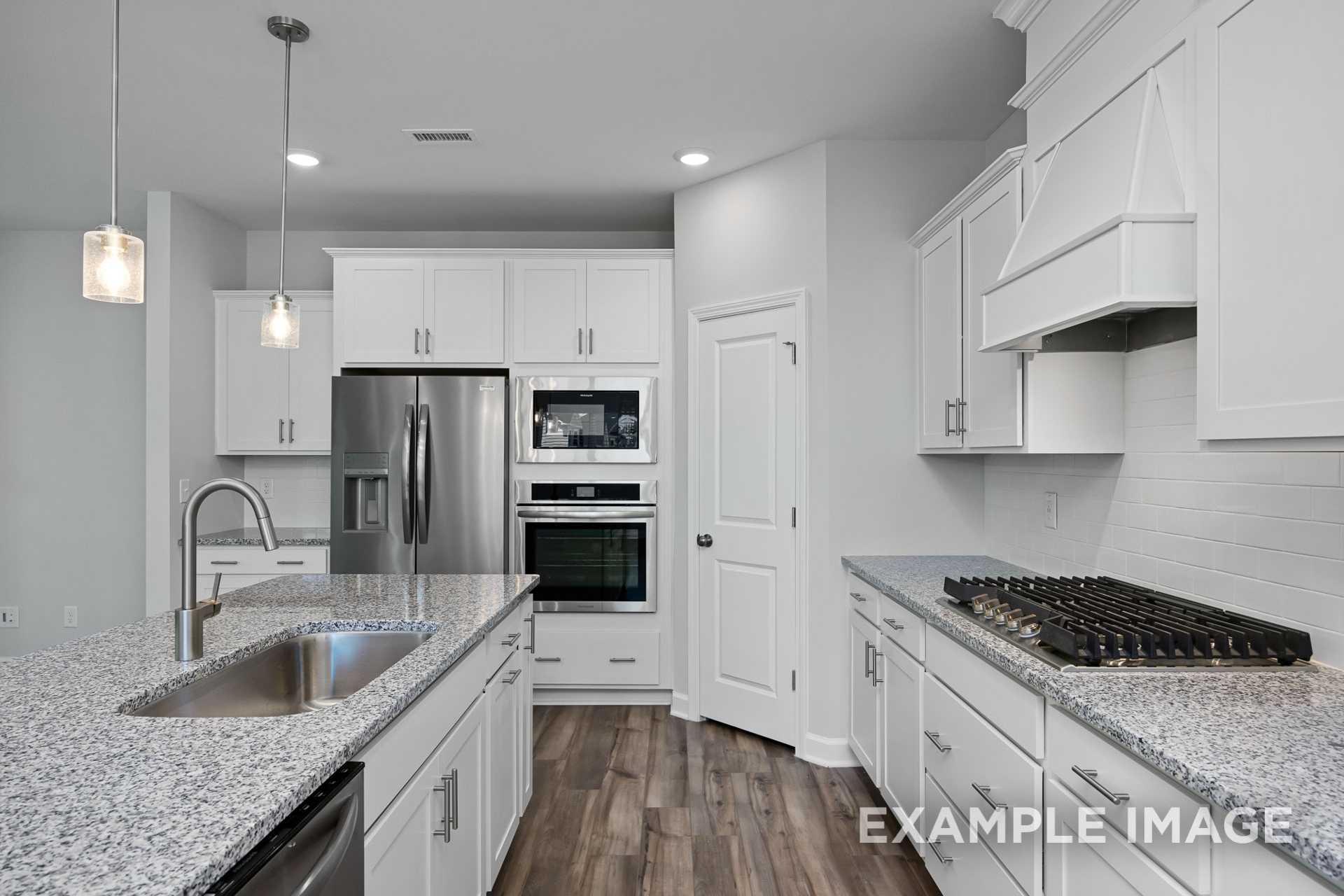 Modern Preston B kitchen featuring white shaker cabinets, stainless steel appliances, granite island sink, and hardwood floors
