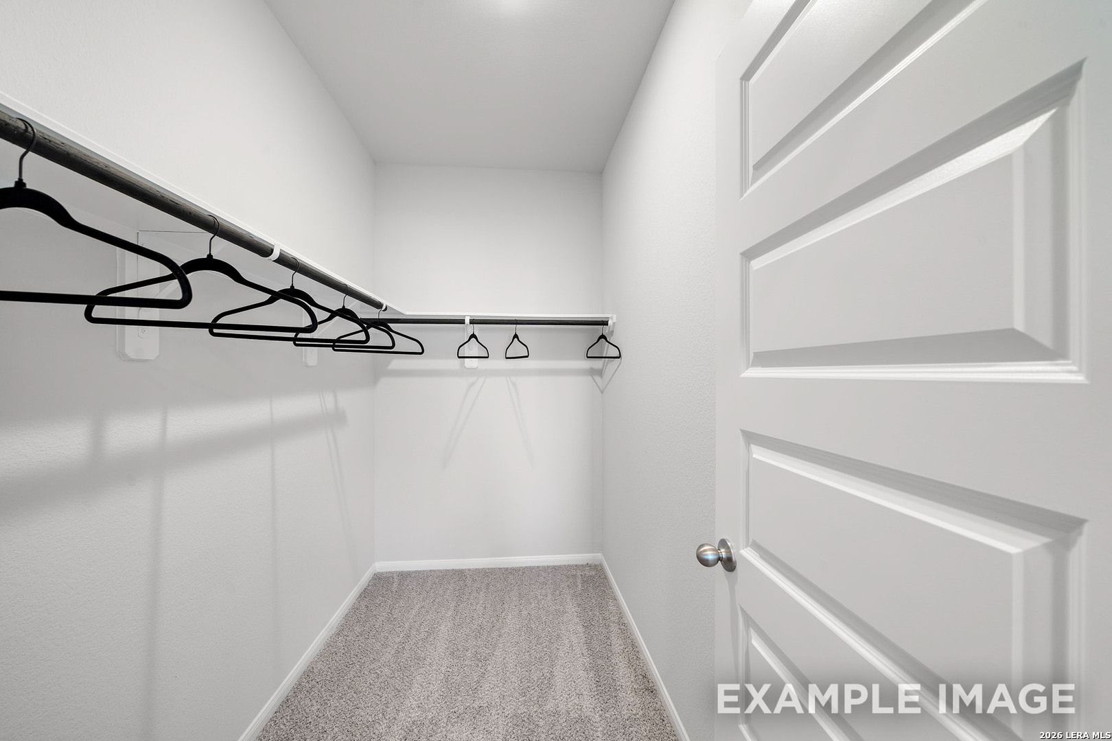 Walk-in closet with shelving and carpeted floors in The San Marcos F floor plan by Davidson Homes, San Antonio, Texas.