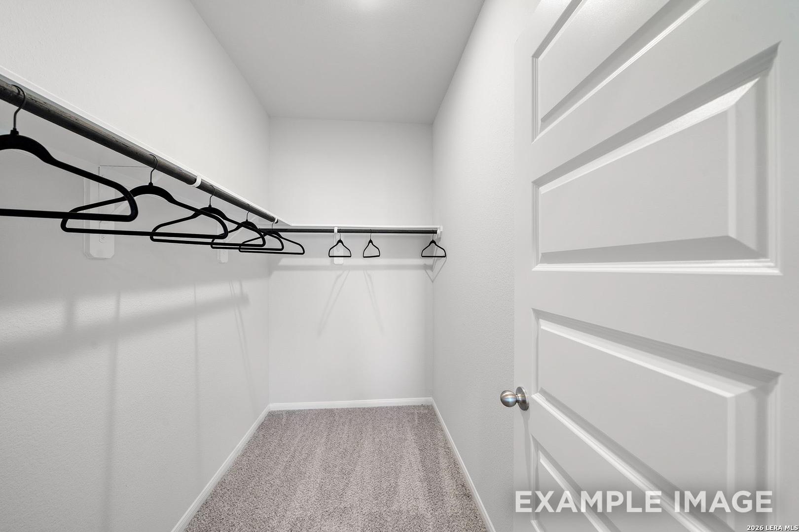 Walk-in closet with shelving and carpeted floors in The San Marcos F floor plan by Davidson Homes, San Antonio, Texas.