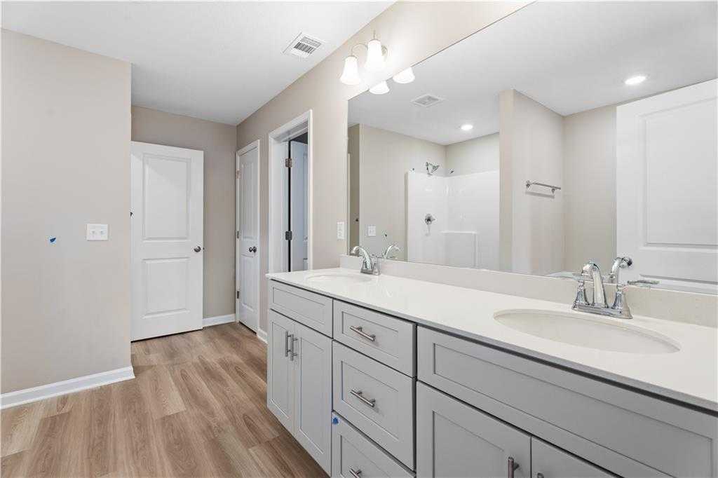 Modern master bathroom featuring double vanity sinks, large mirror, and walk-in shower in Davidson Homes The Bartlett, Phenix City, Alabama