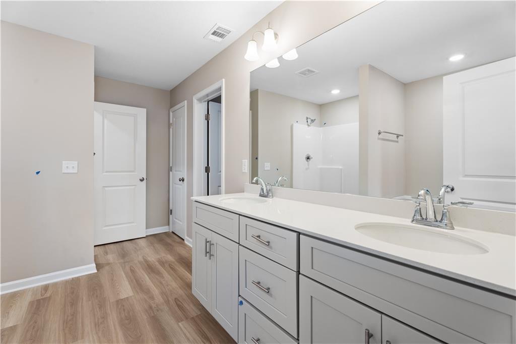 Modern master bathroom featuring double vanity sinks, large mirror, and walk-in shower in Davidson Homes The Bartlett, Phenix City, Alabama