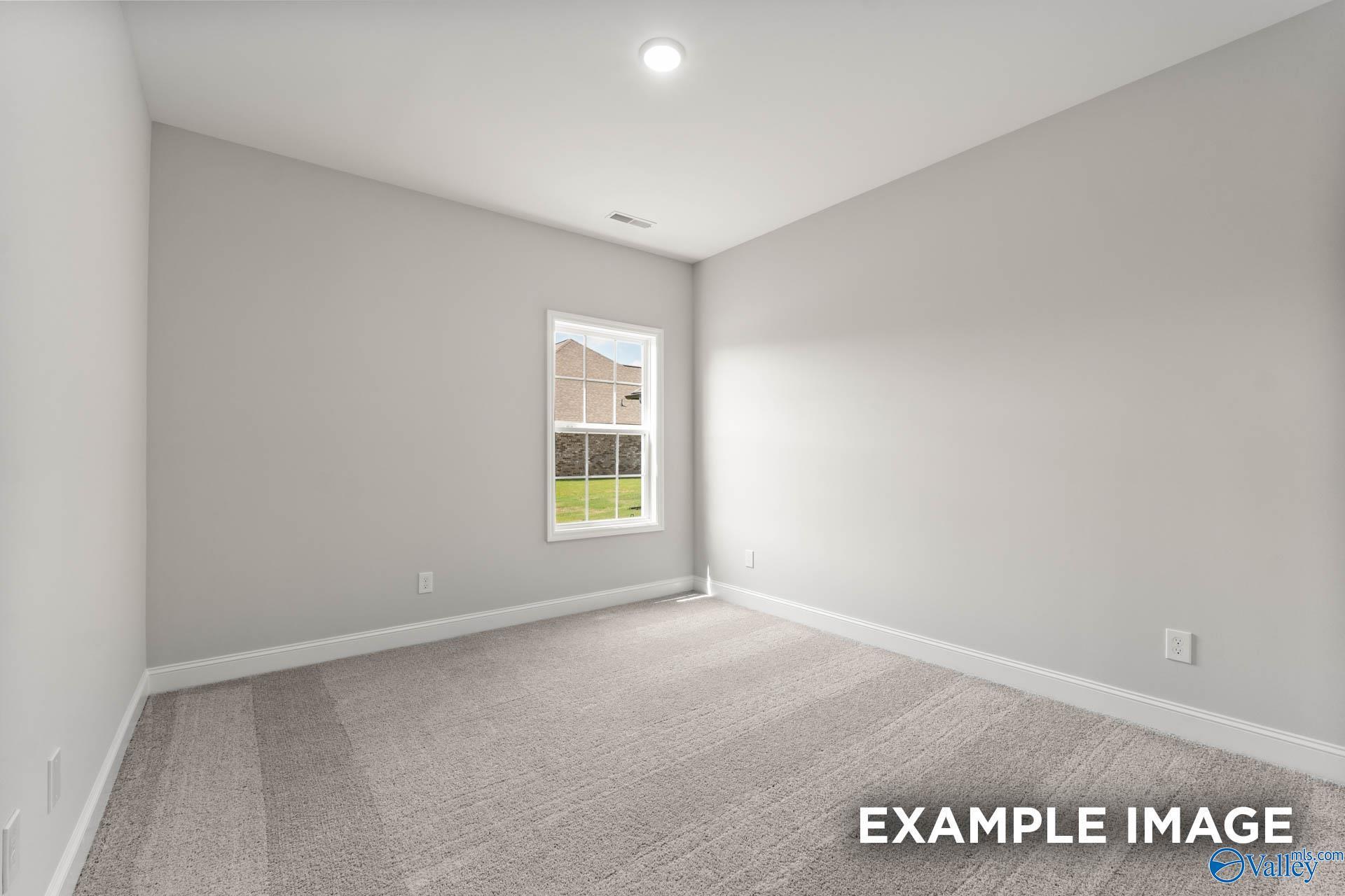 Bright, neutral-toned bedroom with plush carpet in The Madison A floor plan by Davidson Homes in Athens, Alabama.