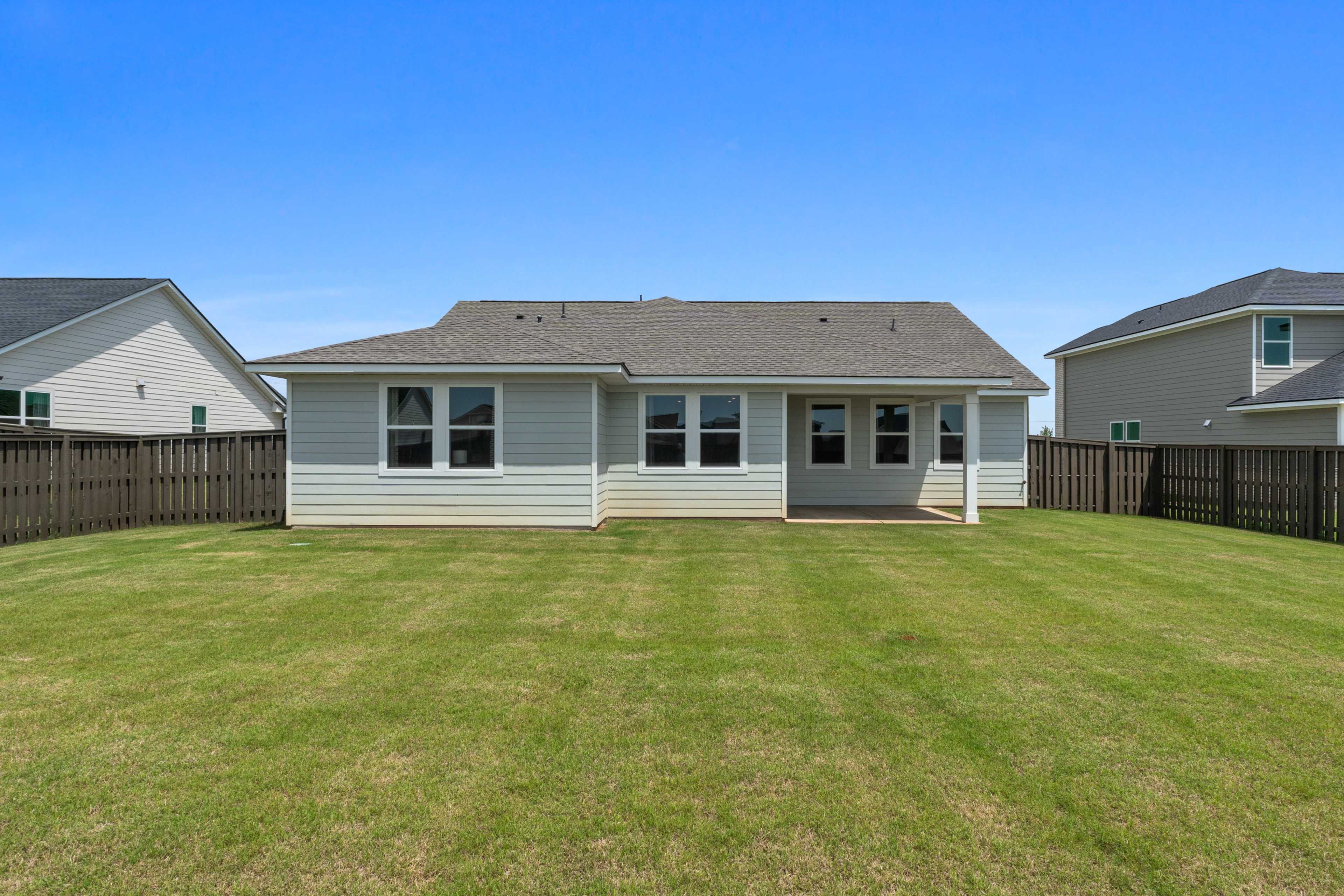 Spacious backyard patio at Anderson Farm in Athens Alabama with fenced lawn and modern gray home exterior