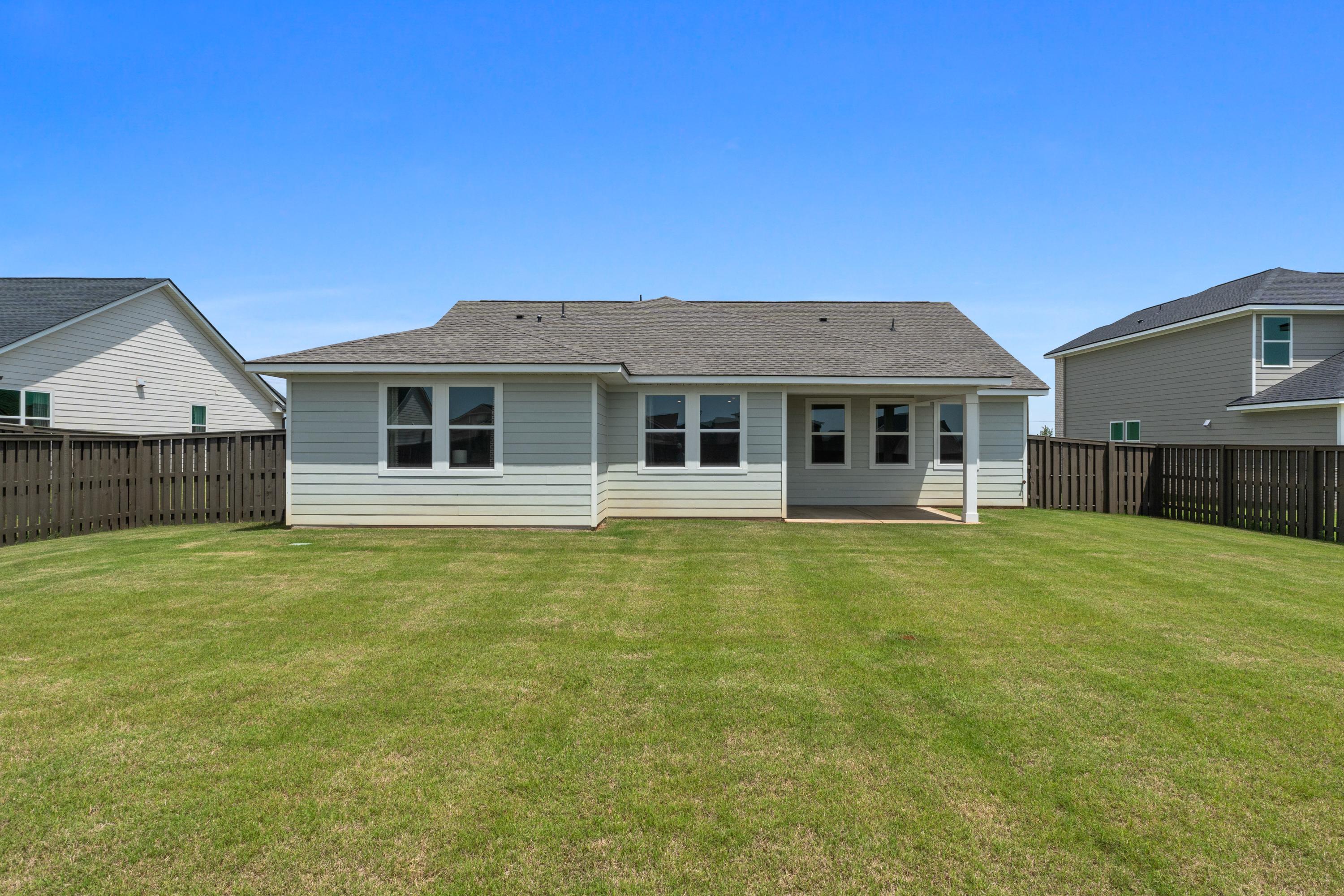 Spacious backyard patio at Anderson Farm in Athens Alabama with fenced lawn and modern gray home exterior