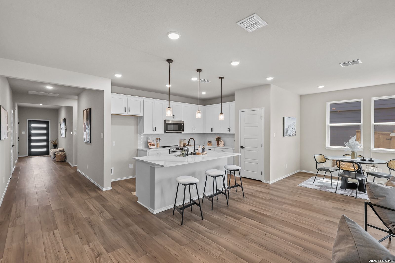 Modern open-concept kitchen with white cabinets and island in The Daphne H floor plan at Hannah Heights, Seguin, Texas.