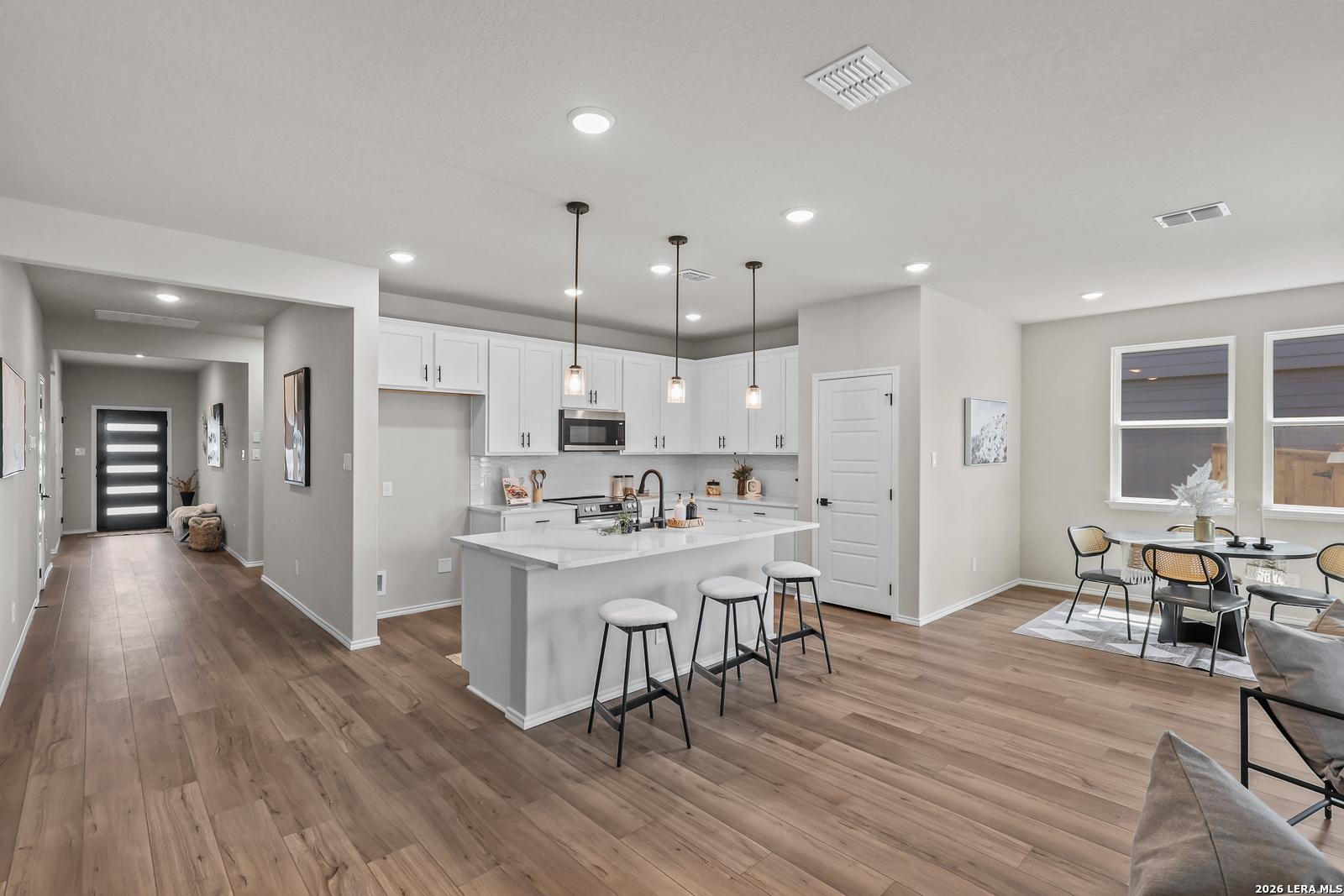 Modern open-concept kitchen with white cabinets and island in The Daphne H floor plan at Hannah Heights, Seguin, Texas.