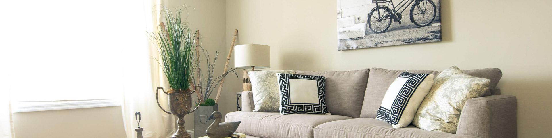 Cozy living room at Summer Pointe in Madison Alabama with beige sofa, rustic wood coffee table, bicycle wall art, and natural light