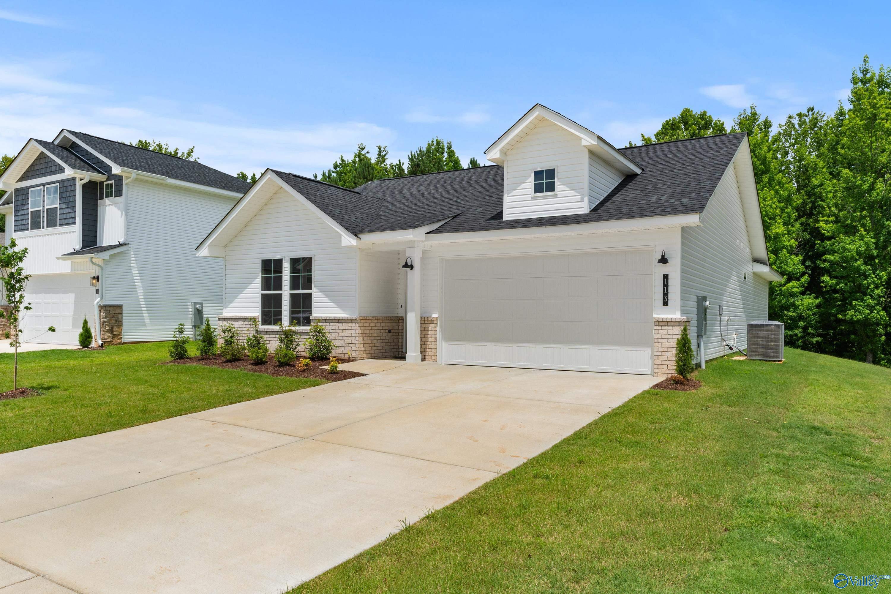 Modern white single-story home with 2-car garage, brick accents, and lush landscaping in Forest Glen, Hazel Green, Alabama - Davidson Homes The Phoenix